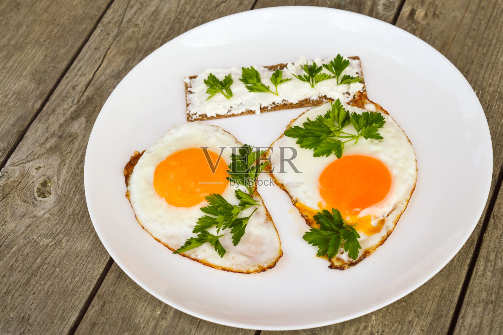 健康早餐:煎蛋、芝士面包和新鲜欧芹放在白色的盘子里照片摄影图片