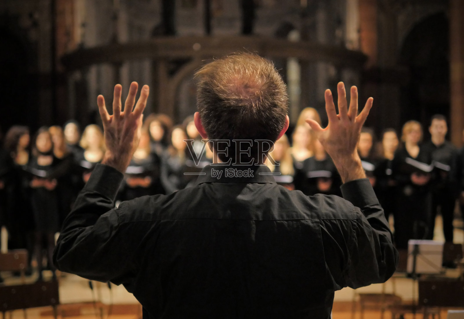 一位音乐家在大教堂的音乐会上指挥唱诗班。照片摄影图片