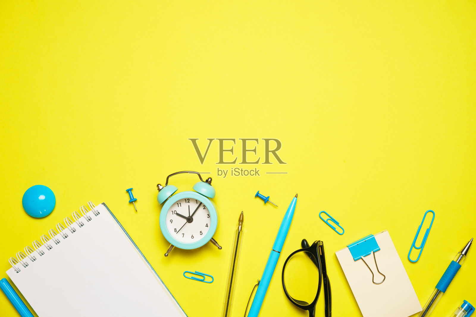 笔记本书写笔和闹钟与眼镜在黄色背景顶部照片摄影图片
