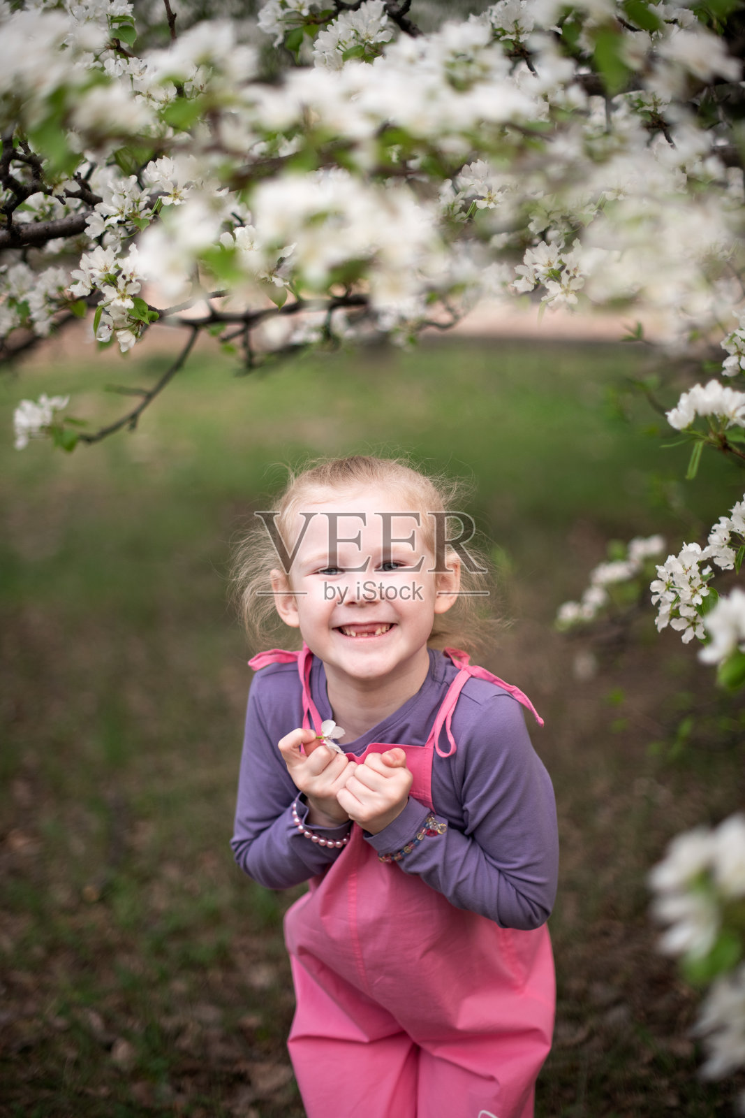 一个金发女孩在花园里微笑的肖像。照片摄影图片