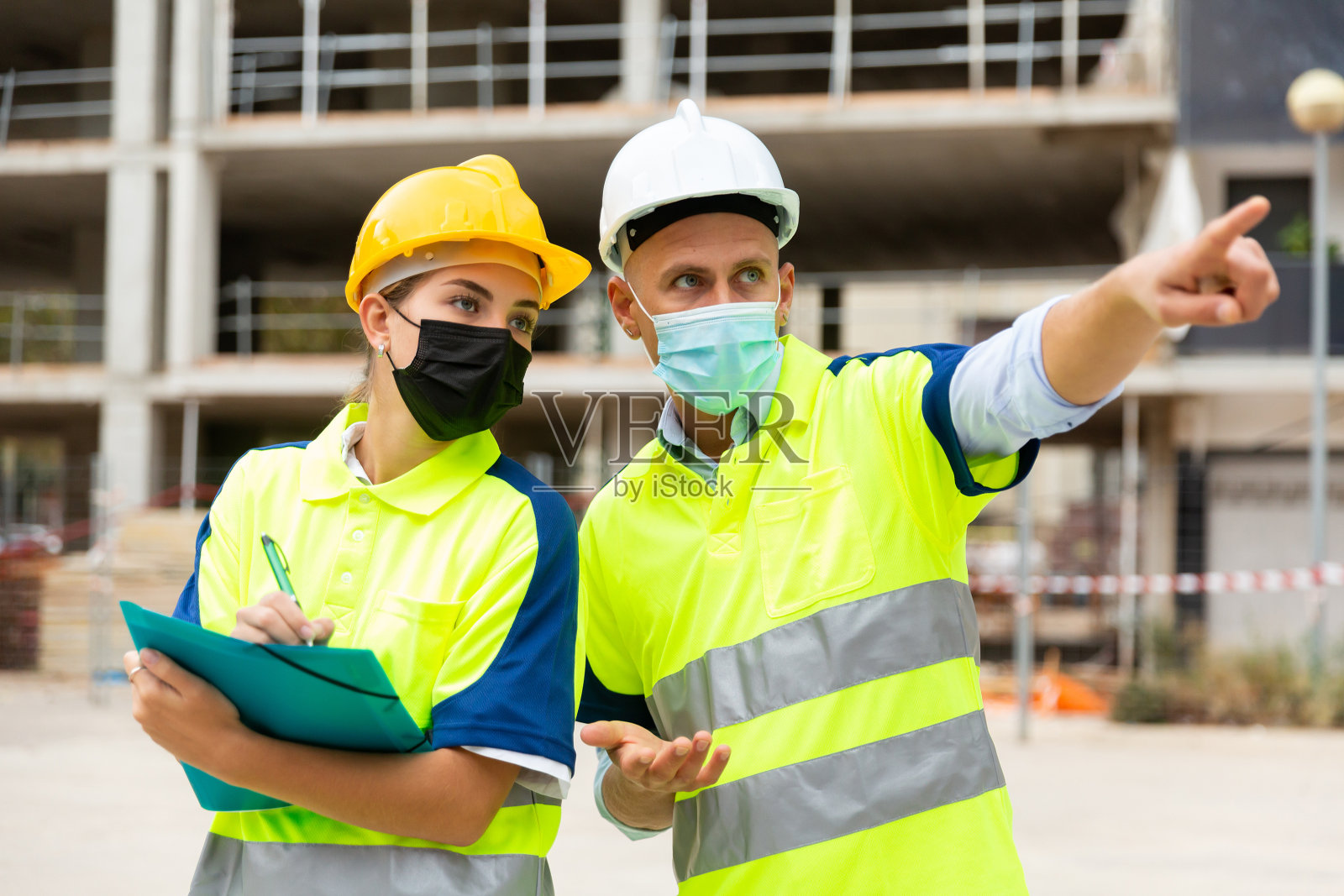 戴着面具的男女建筑工在工地上交谈照片摄影图片