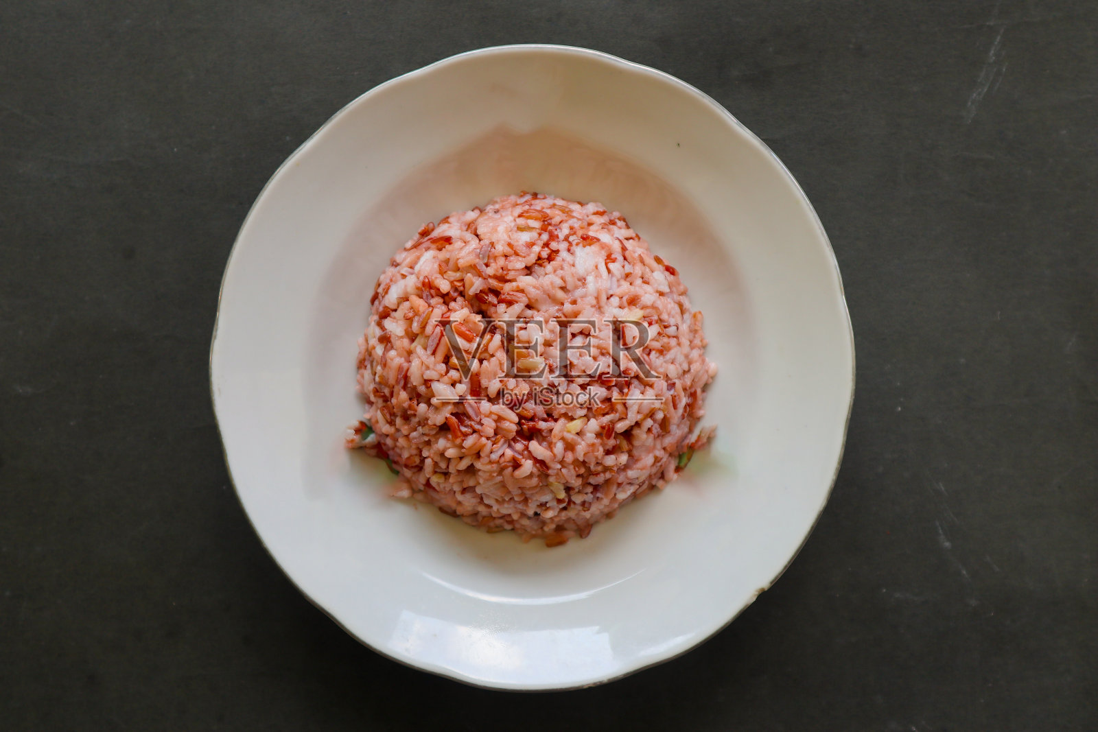 红色蒸饭或印度炒饭放在盘子里，在黑色背景上分开照片摄影图片