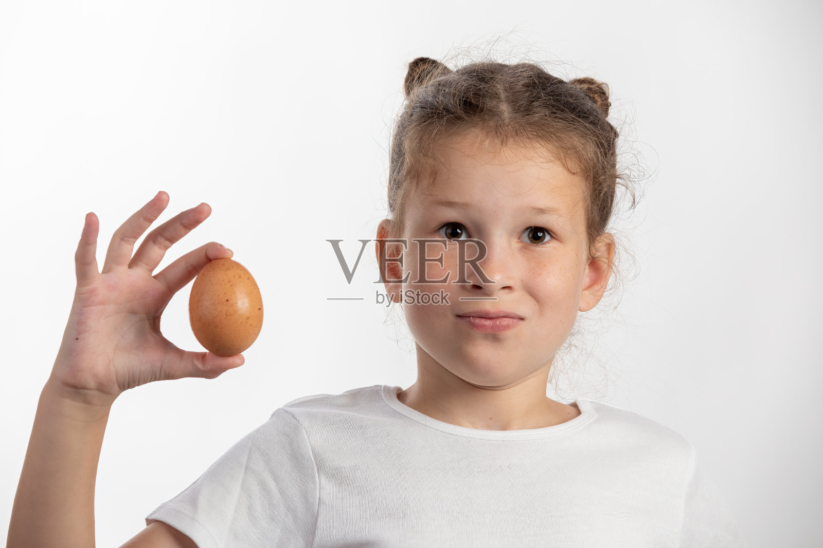 小女孩拿着一个鸡蛋-在白色的背景照片摄影图片