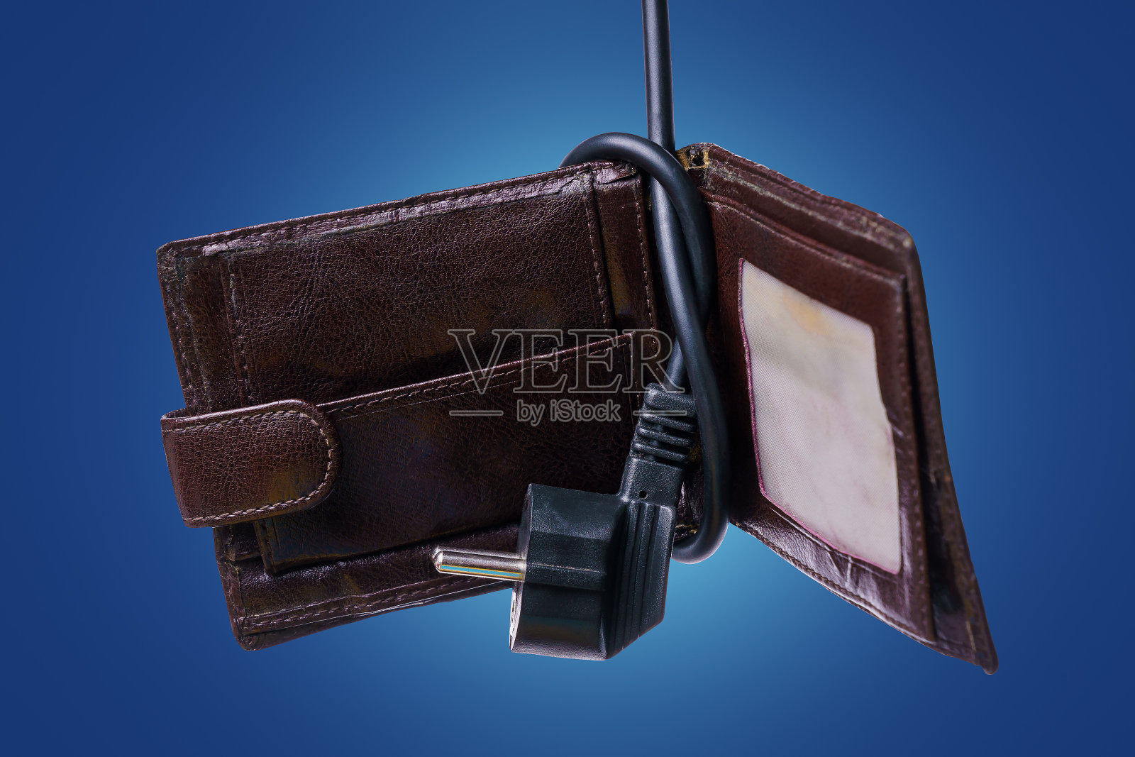 在旧钱包上打结的有插头的电线。能源危机的概念照片摄影图片