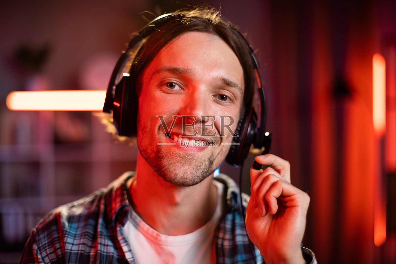 英俊的年轻人晚上在家工作时戴着耳机。照片摄影图片