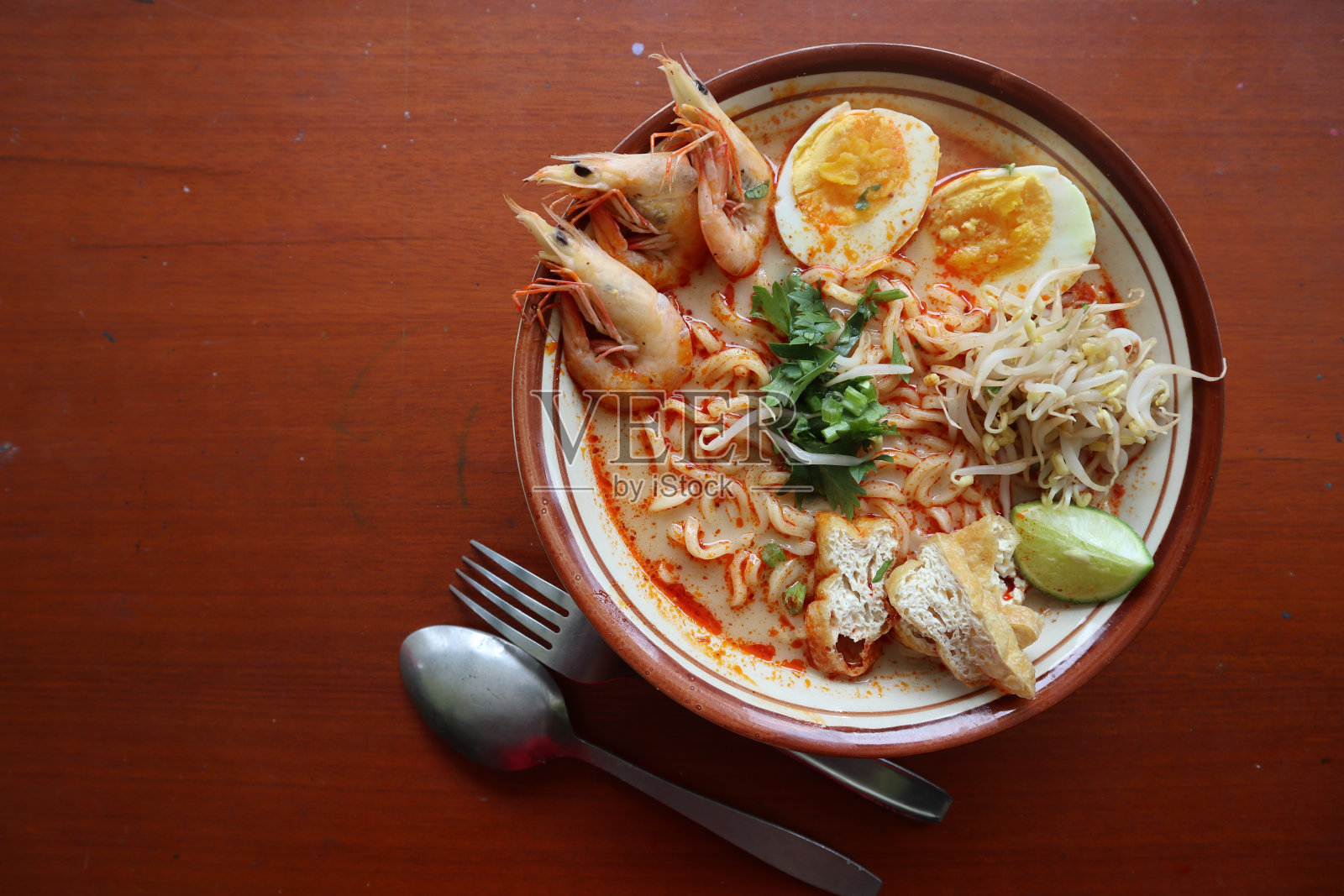 叻沙，叻沙咖喱由粉丝、面条、豆芽、鸡蛋、豆腐青柠和虾制成，汤汁辛辣，富含香料。叻沙盛在碗里，孤立在白色背景上。照片摄影图片