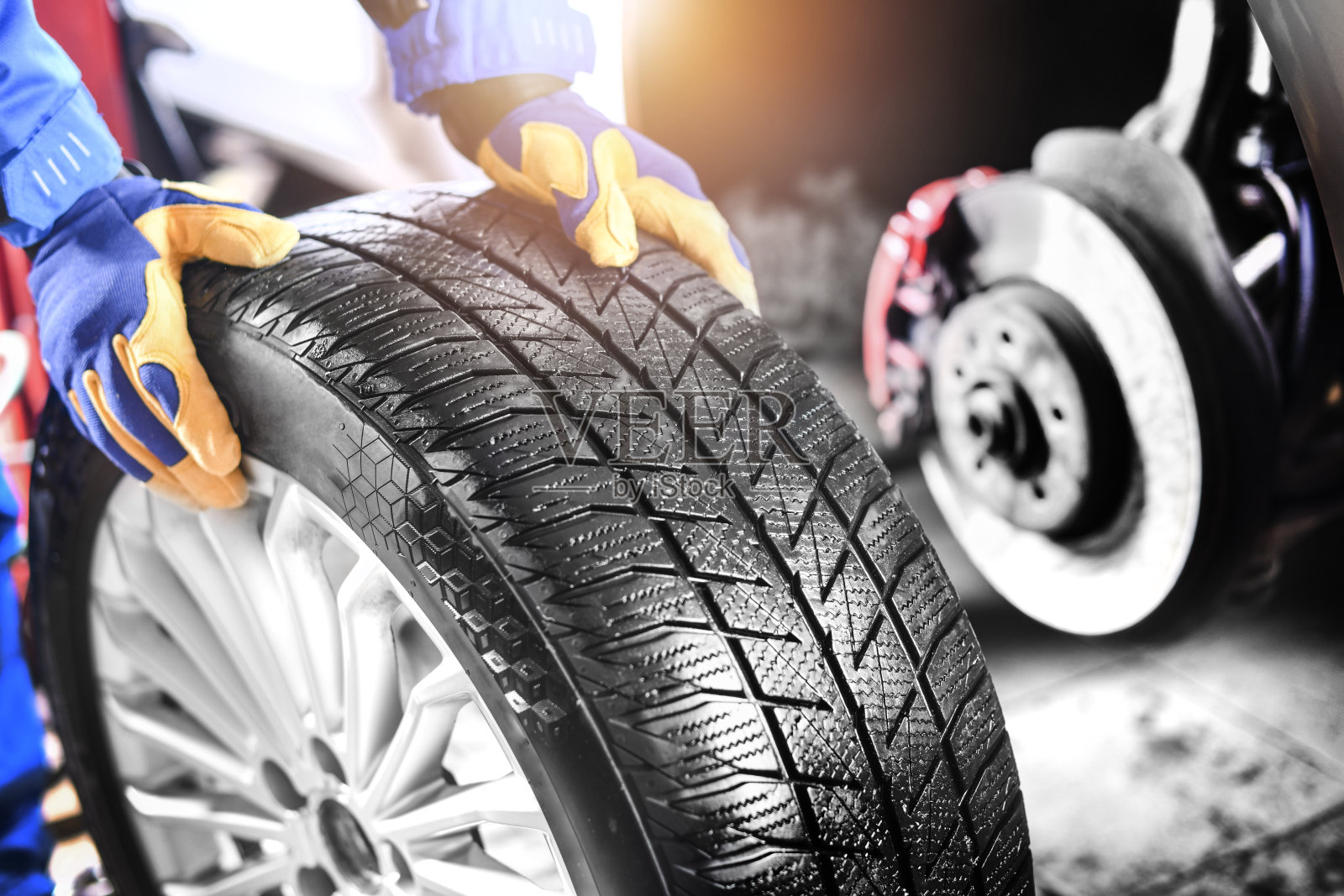 汽车修理工在汽车修理厂工作，更换车轮合金轮胎。照片摄影图片