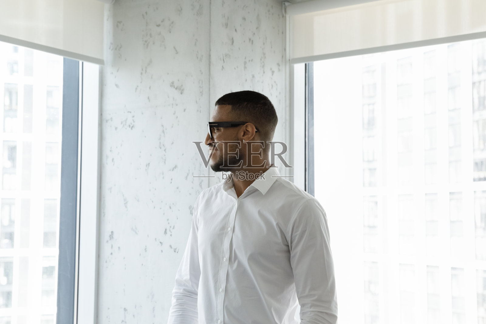 非洲商人站在摩天大楼的办公室里，凝视着城市的景色照片摄影图片