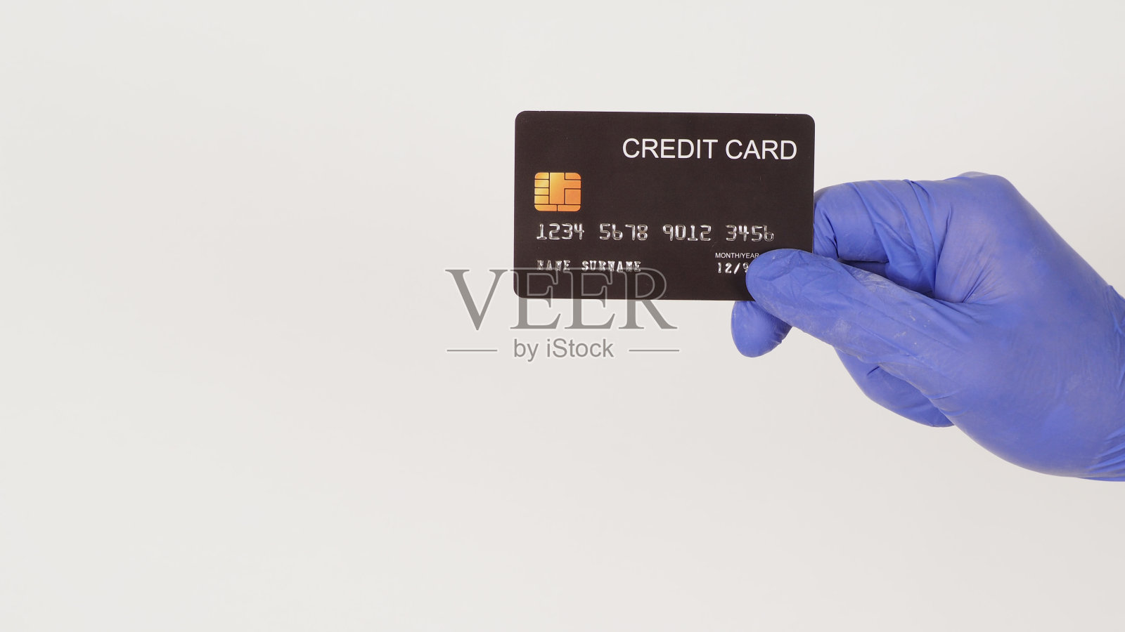 手拿黑色信用卡，戴白色背景上隔离的紫色或紫色乳胶手套。照片摄影图片