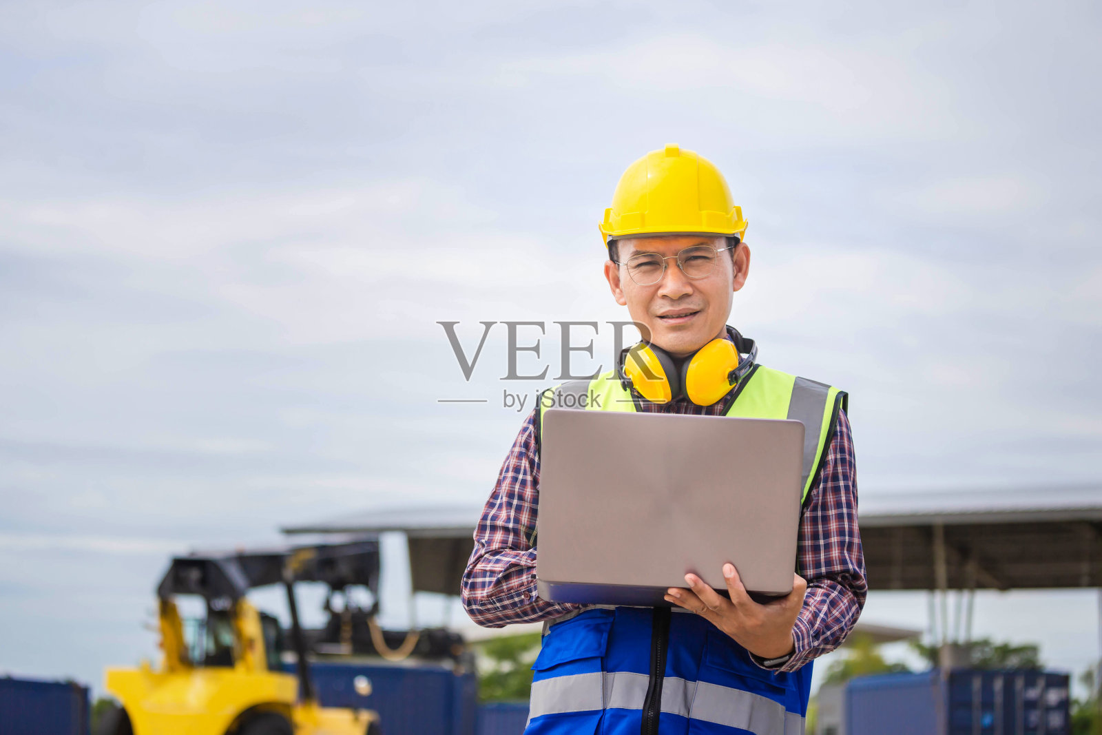 工程师带着手提电脑检查集装箱，领班戴着安全帽和安全背心检查集装箱和货物照片摄影图片