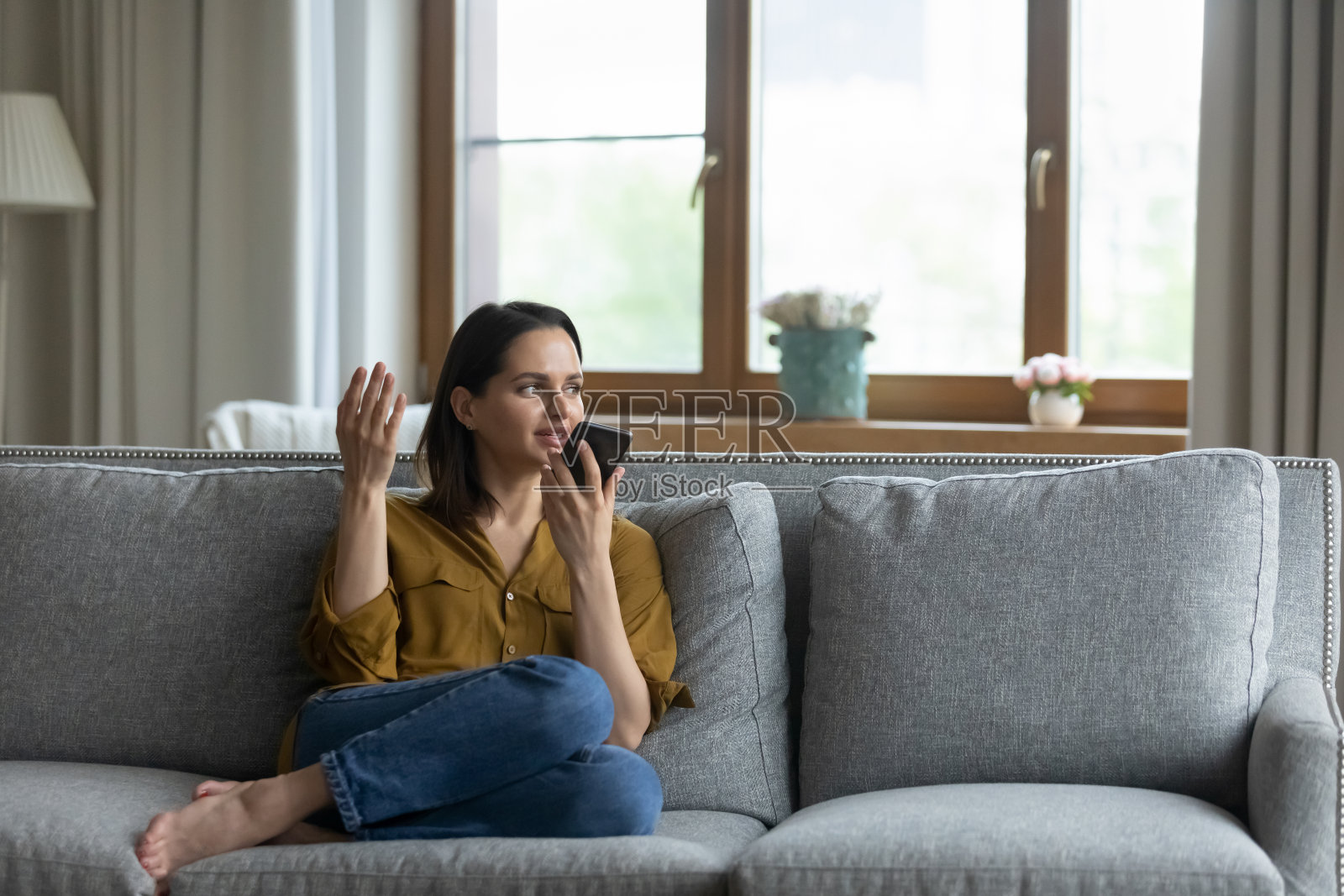 轻松的年轻梦幻的女人录制语音信息在手机上。照片摄影图片