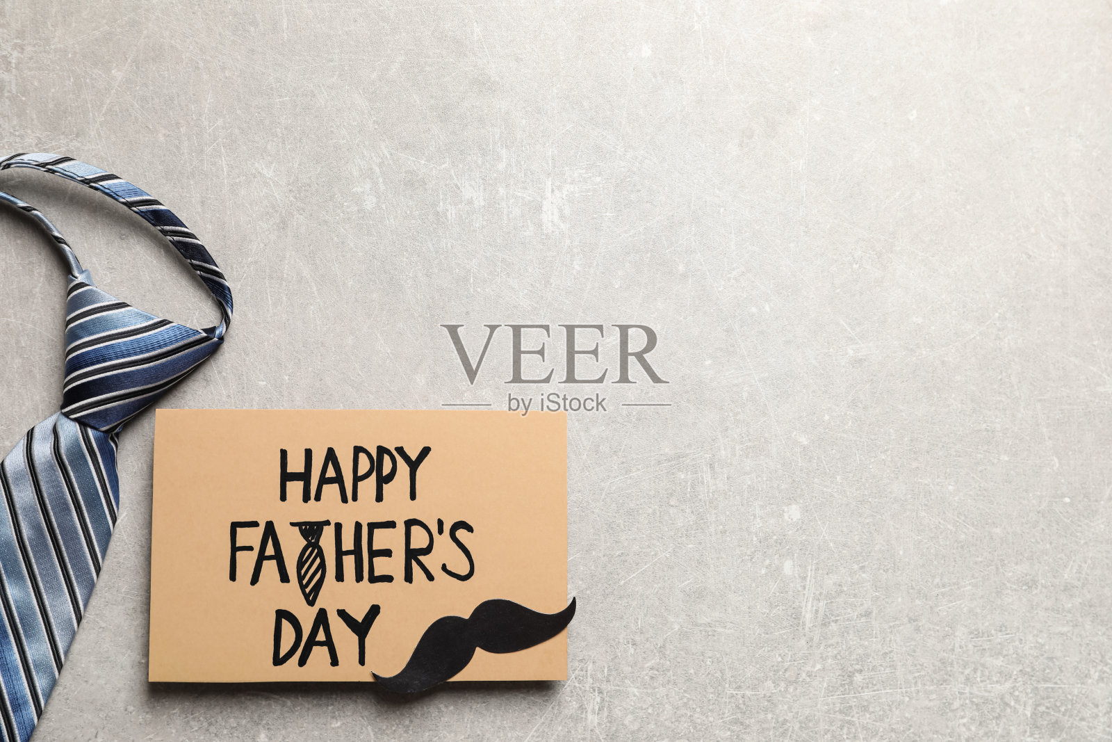 卡片上写着“父亲节快乐”，纸胡子和领带，浅灰色的背景，平铺。空间的文本照片摄影图片
