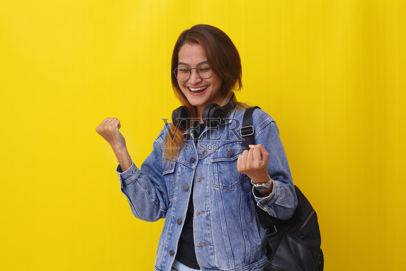 成功的年轻亚洲大学生站着紧握双手。现代生活方式的概念照片摄影图片