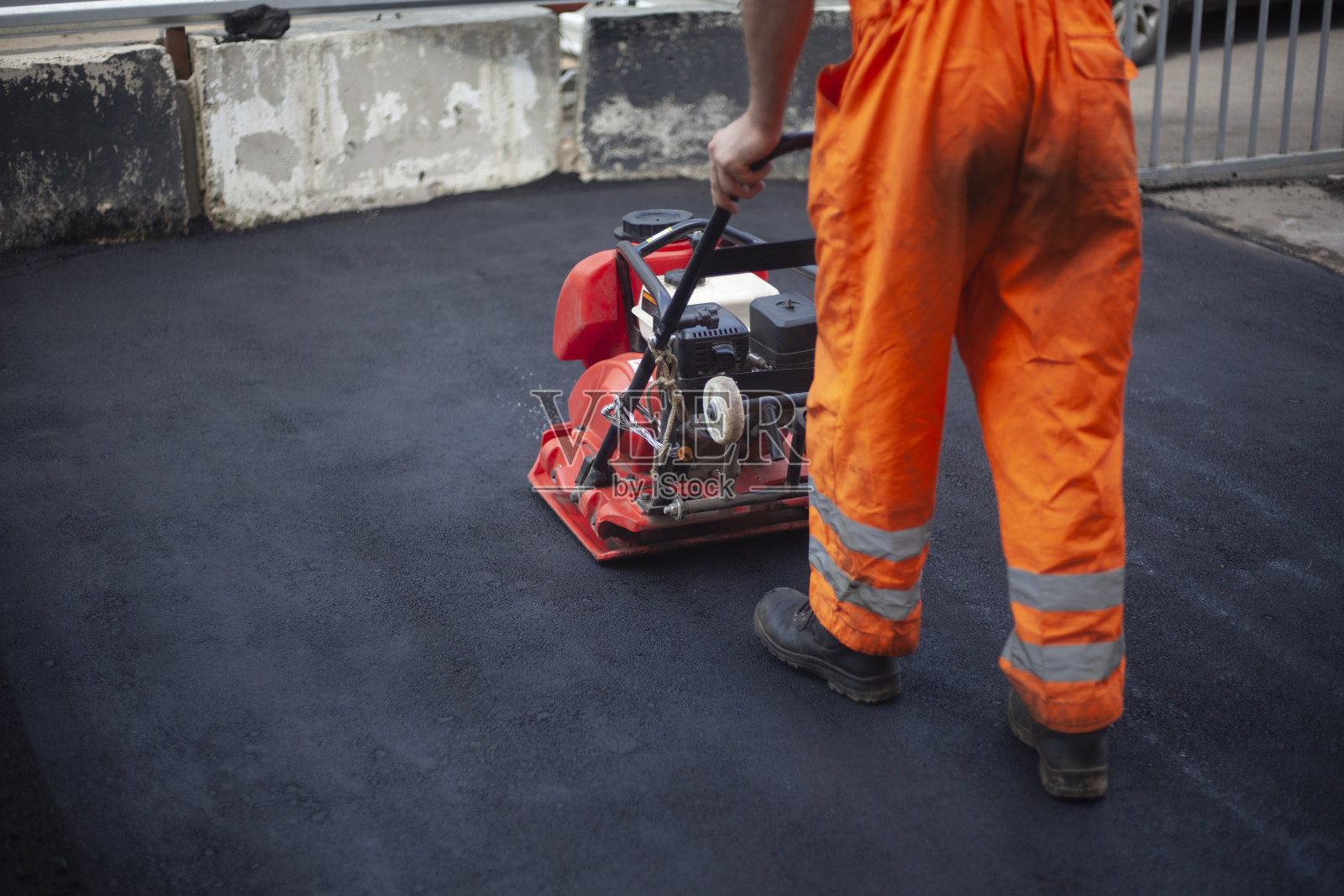 沥青铺设。平整的道路。一名工人正在压缩温热的沥青。照片摄影图片