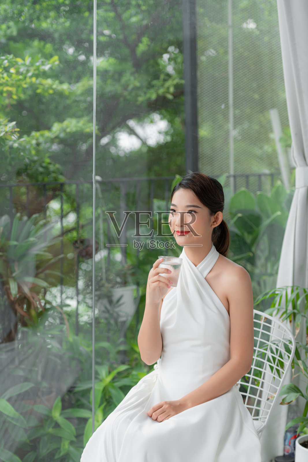 美丽的年轻女子在家里用玻璃杯喝水照片摄影图片