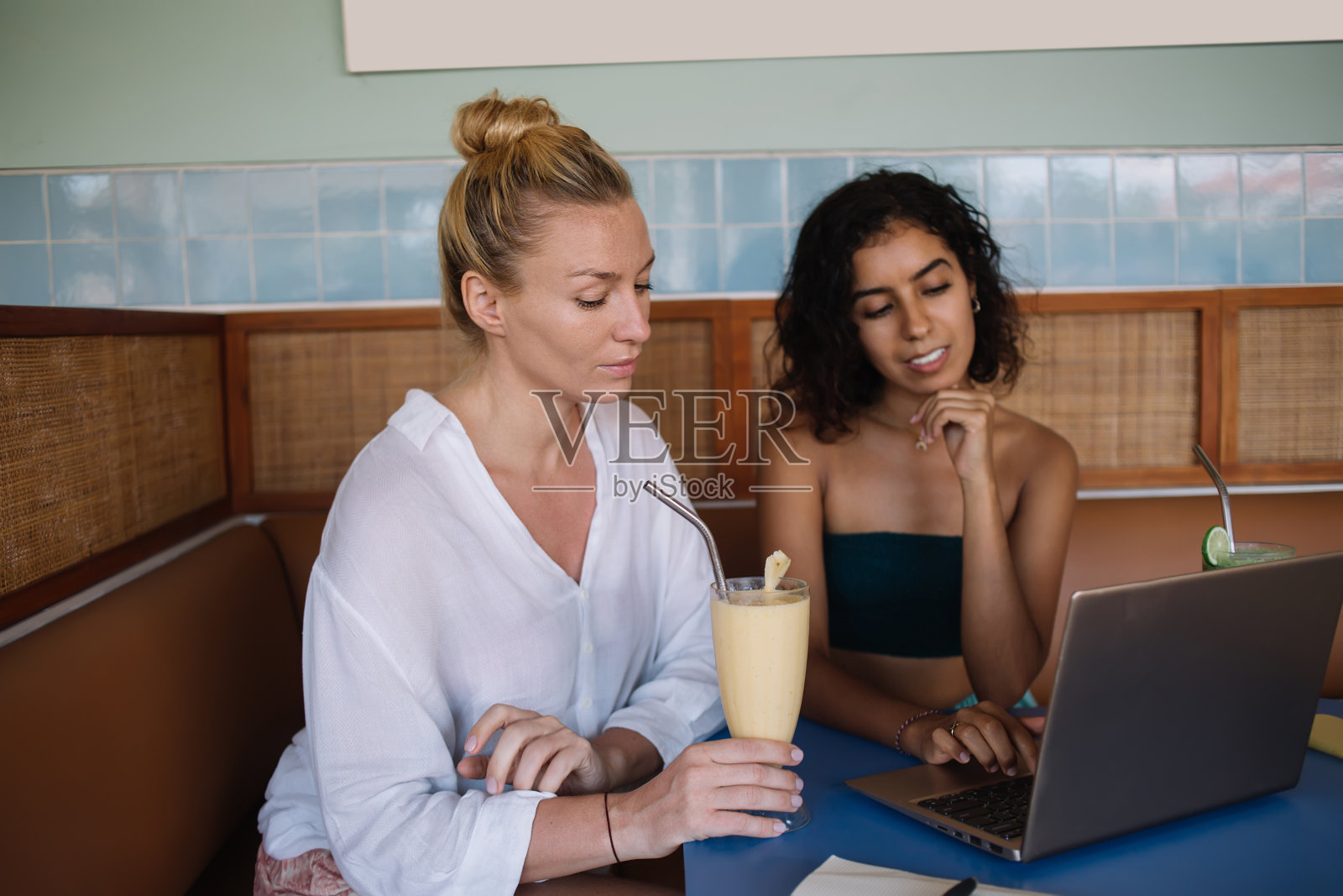 多民族女性朋友在笔记本电脑上工作，喝着清爽的饮料照片摄影图片