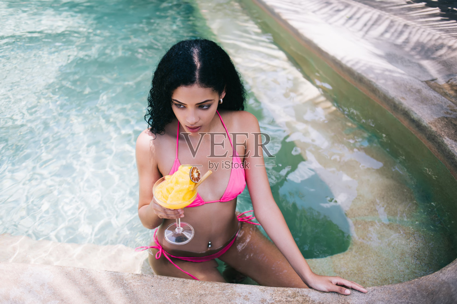 年轻苗条的模特在游泳池里喝饮料照片摄影图片
