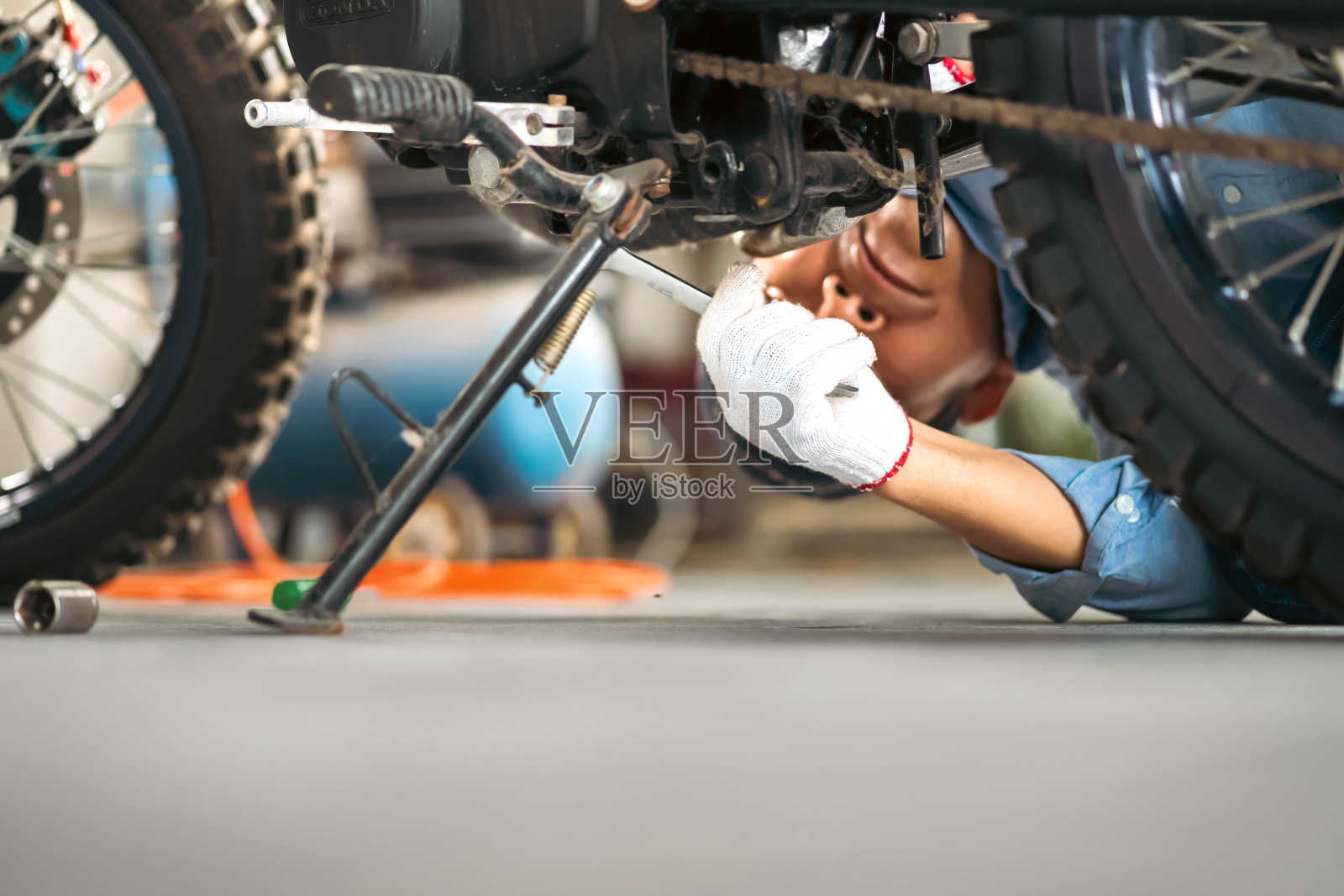 车库或车间的机械师在维修过程中检查经典摩托车的照片。照片摄影图片
