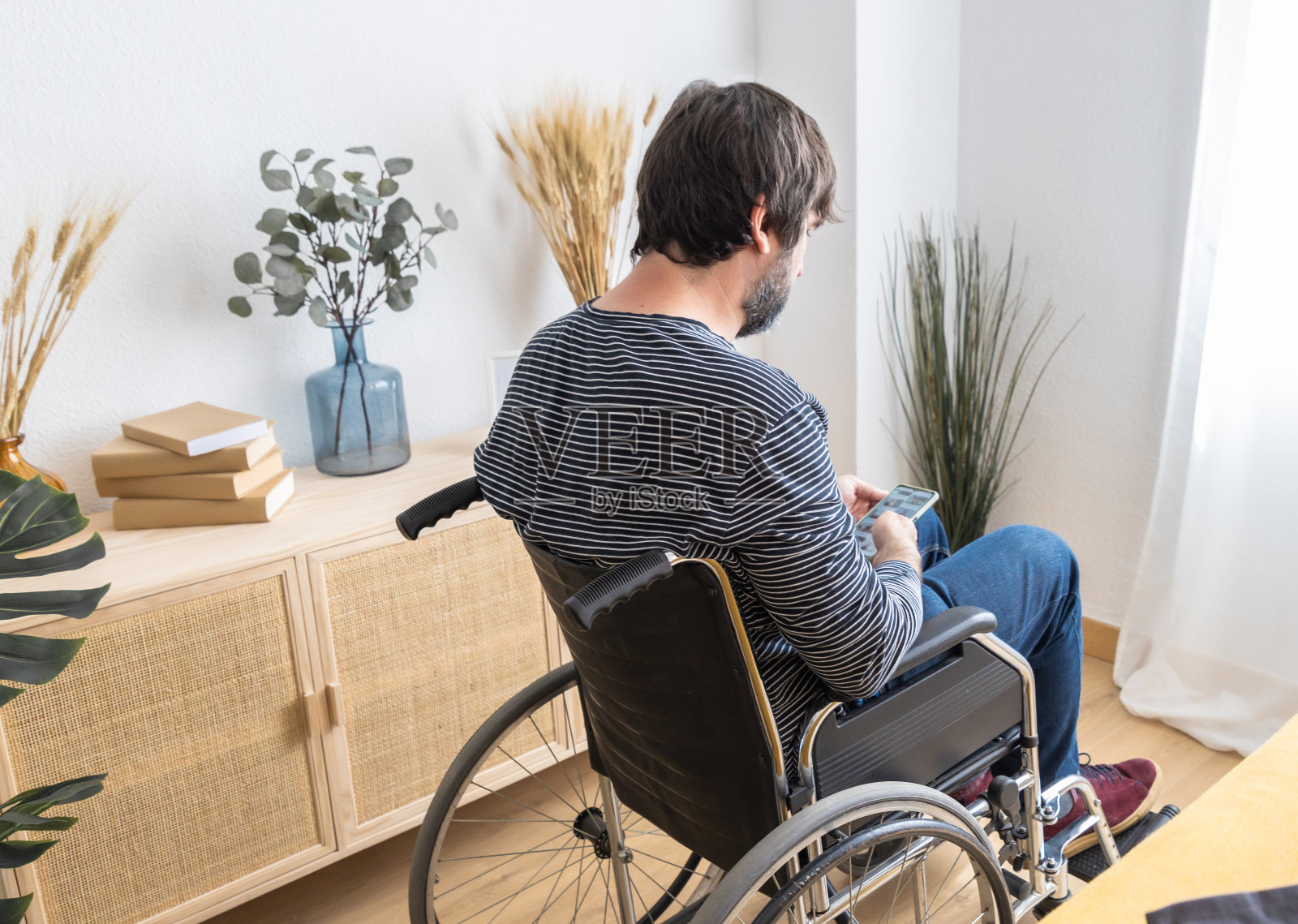 一个坐轮椅的成年男子在家里用手机照片摄影图片