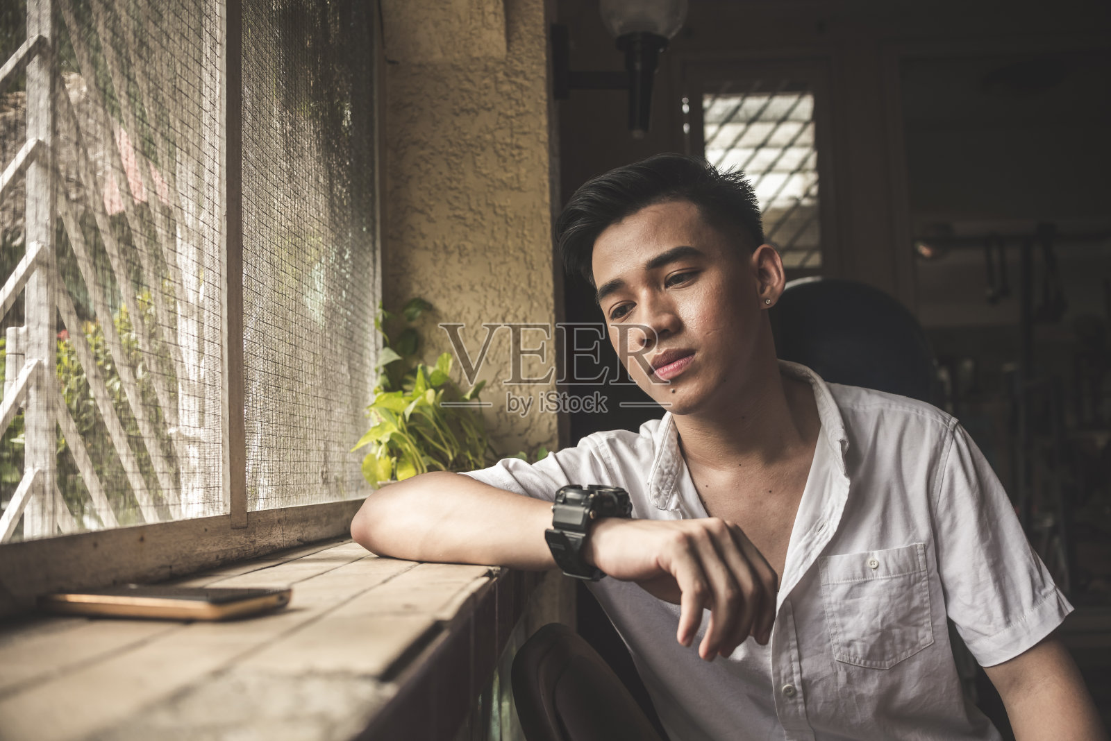 在昏暗房间里焦急等待女友回复消息的年轻男人照片摄影图片