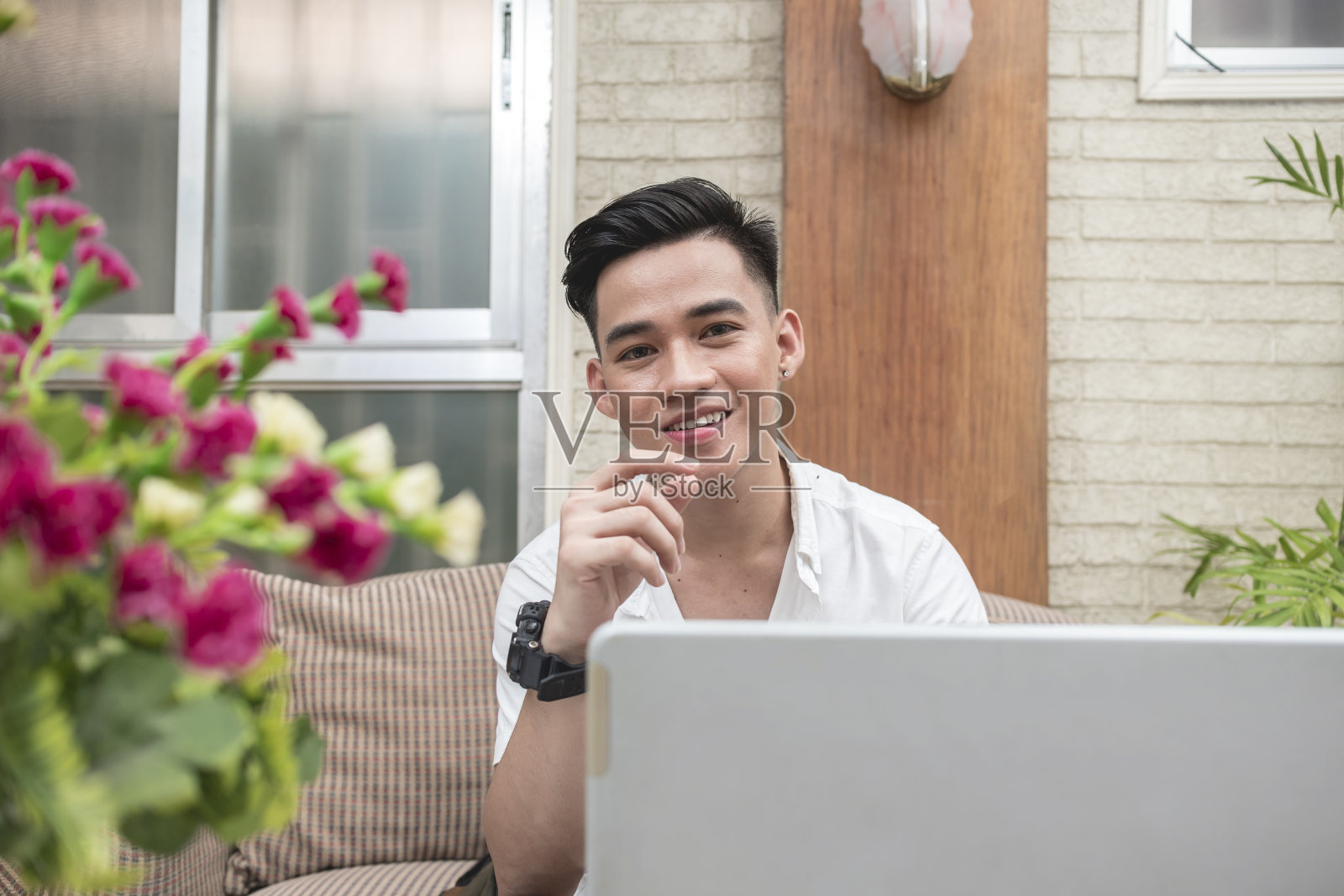 一个积极英俊的虚拟助理在他客厅的沙发上工作。方便的工作环境。照片摄影图片