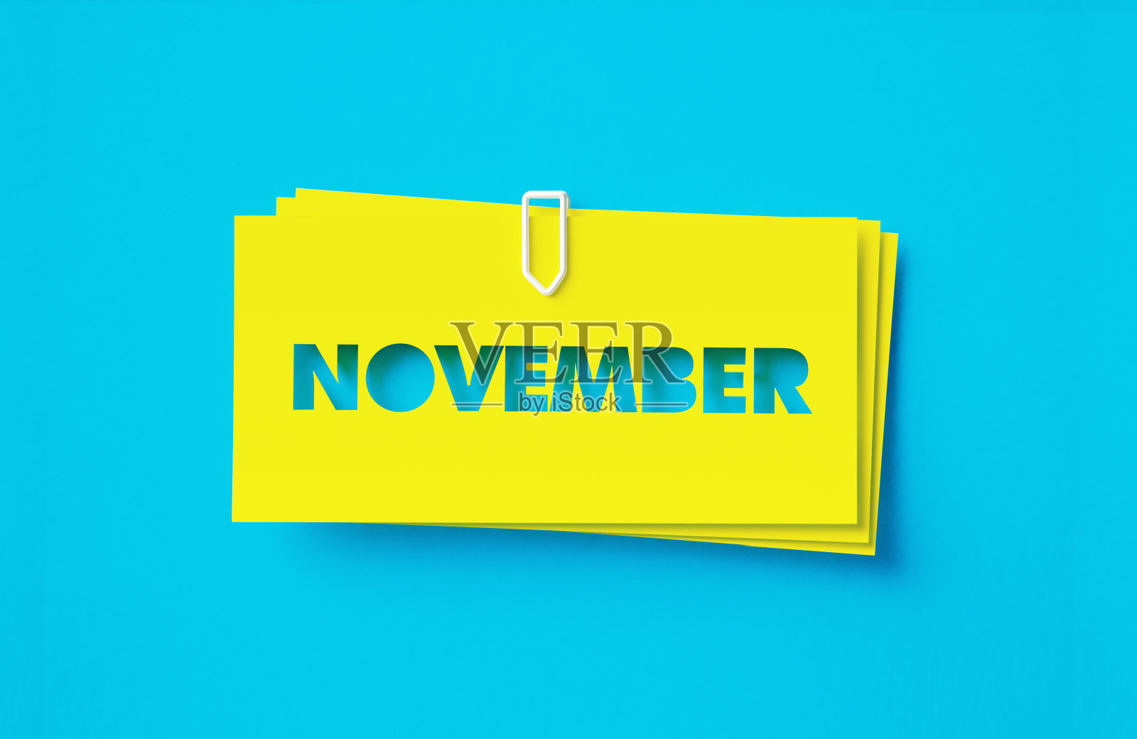 11月写了剪出黄色的不干胶笔记坐在蓝色的背景照片摄影图片