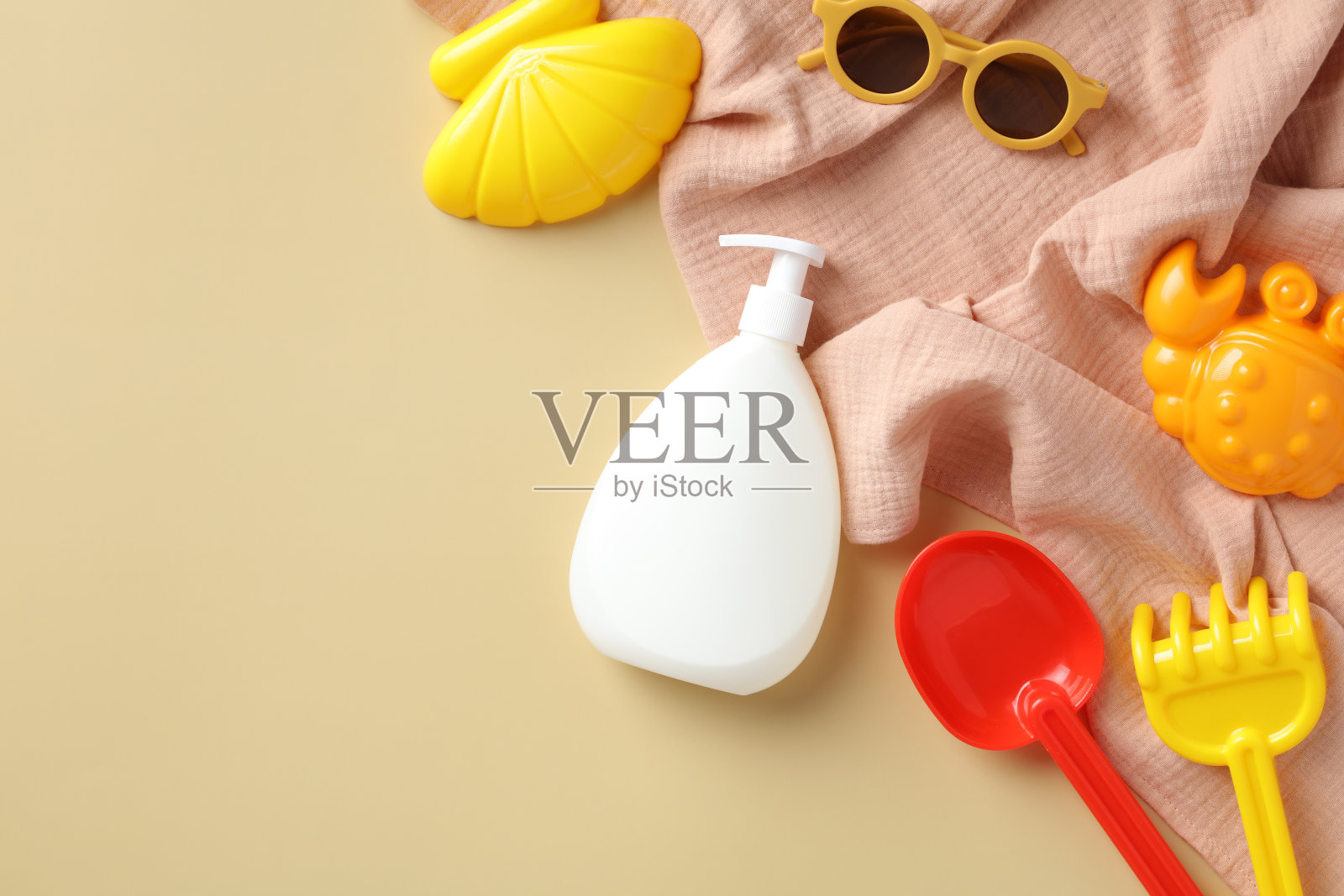 防晒霜乳液瓶，太阳镜，沙模，米色背景的毛巾。儿童防晒化妆品概念。照片摄影图片