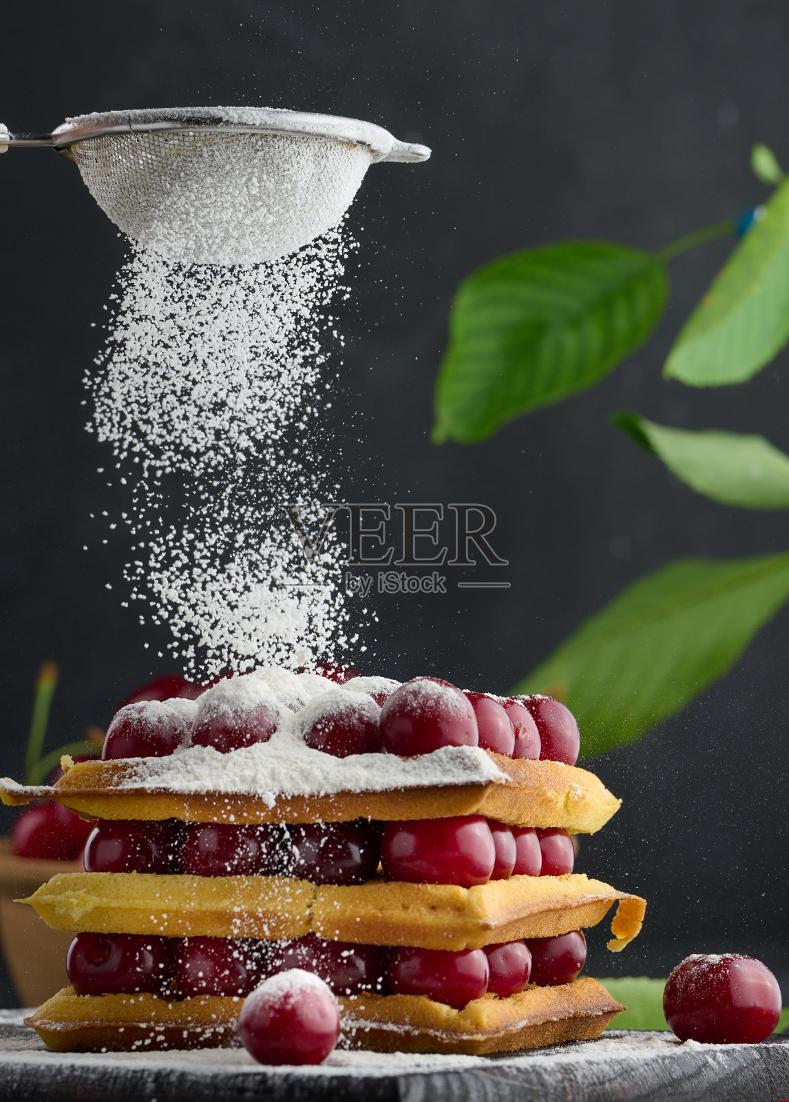 一堆烤比利时华夫饼，配上撒有糖粉的成熟红樱桃照片摄影图片