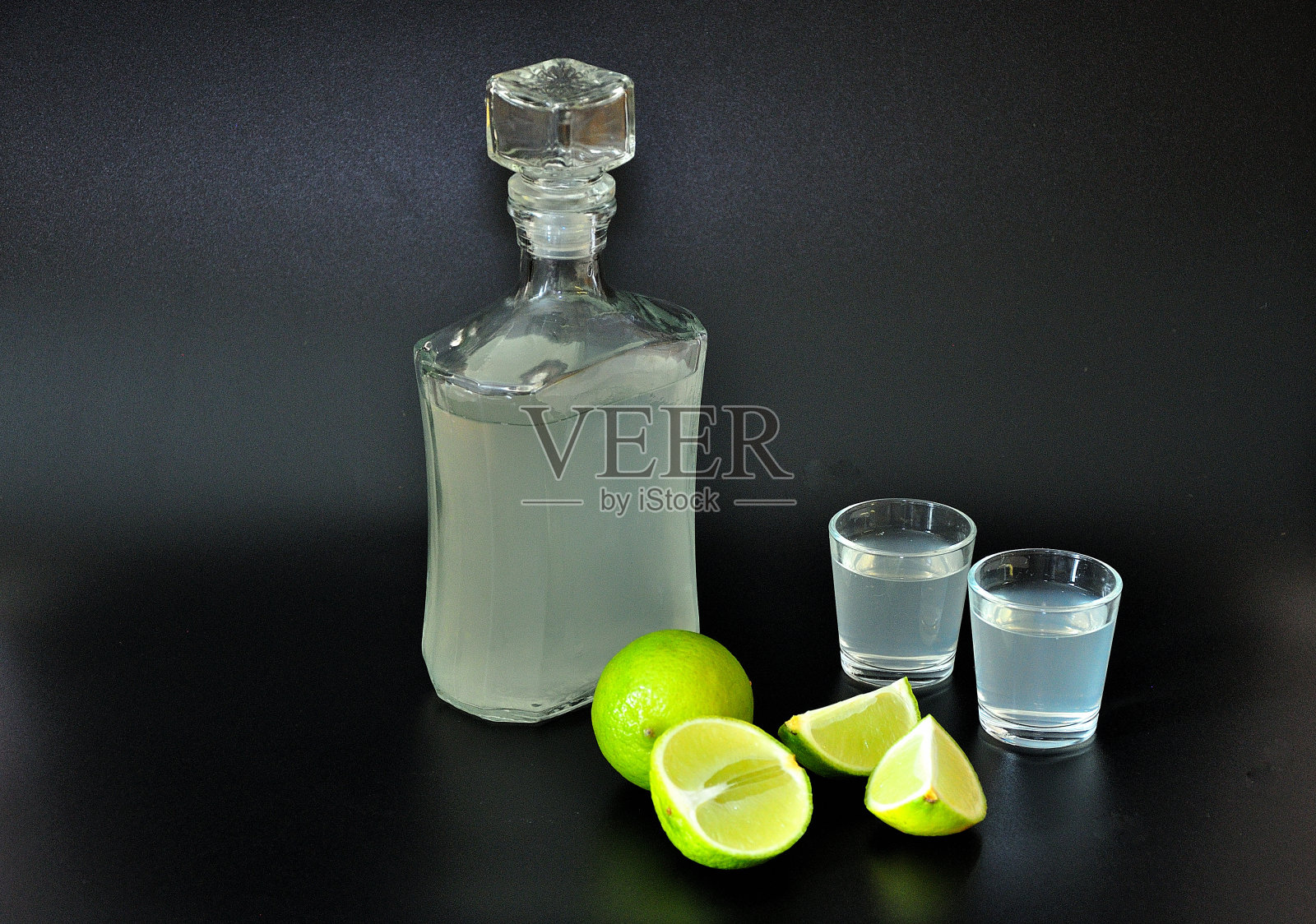 以酸橙为基础的利口酒，强烈的自制酒精和成熟的柑橘片在黑色的背景。照片摄影图片