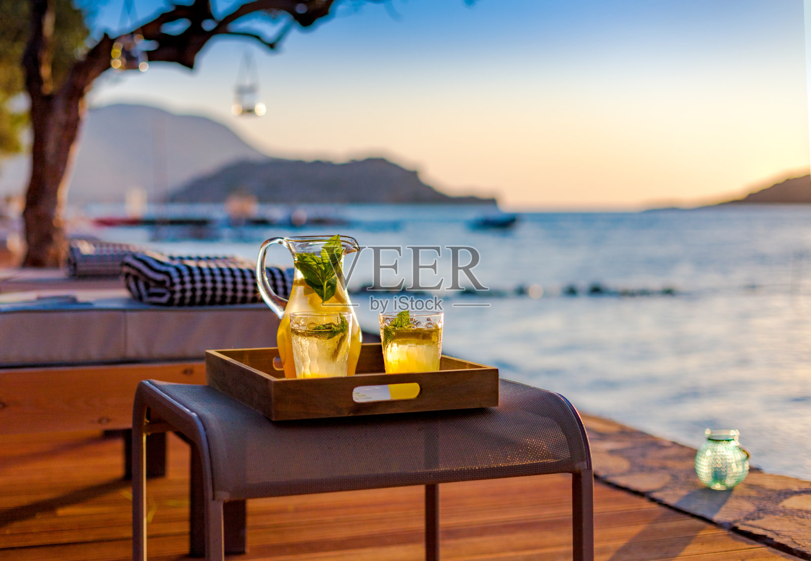 在海边的沙滩上喝柠檬水。照片摄影图片