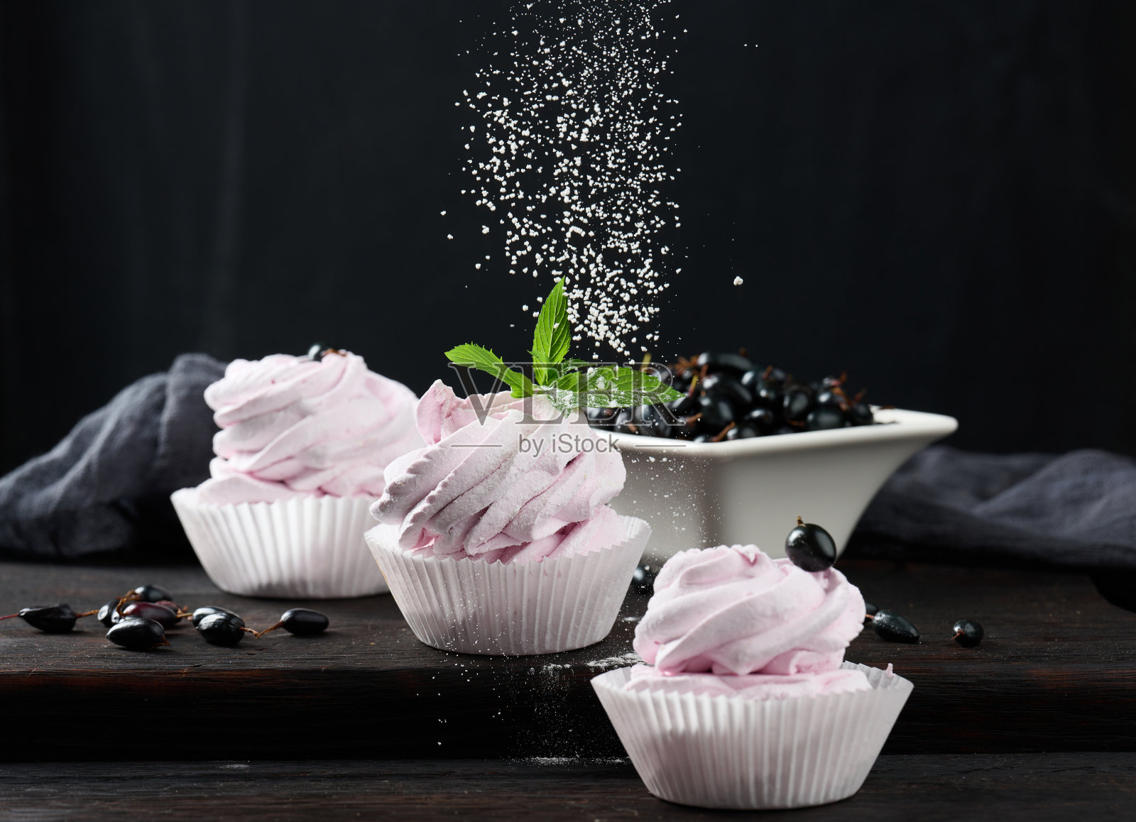 把水果棉花糖分好，装在纸杯里，放在黑色的木板上照片摄影图片