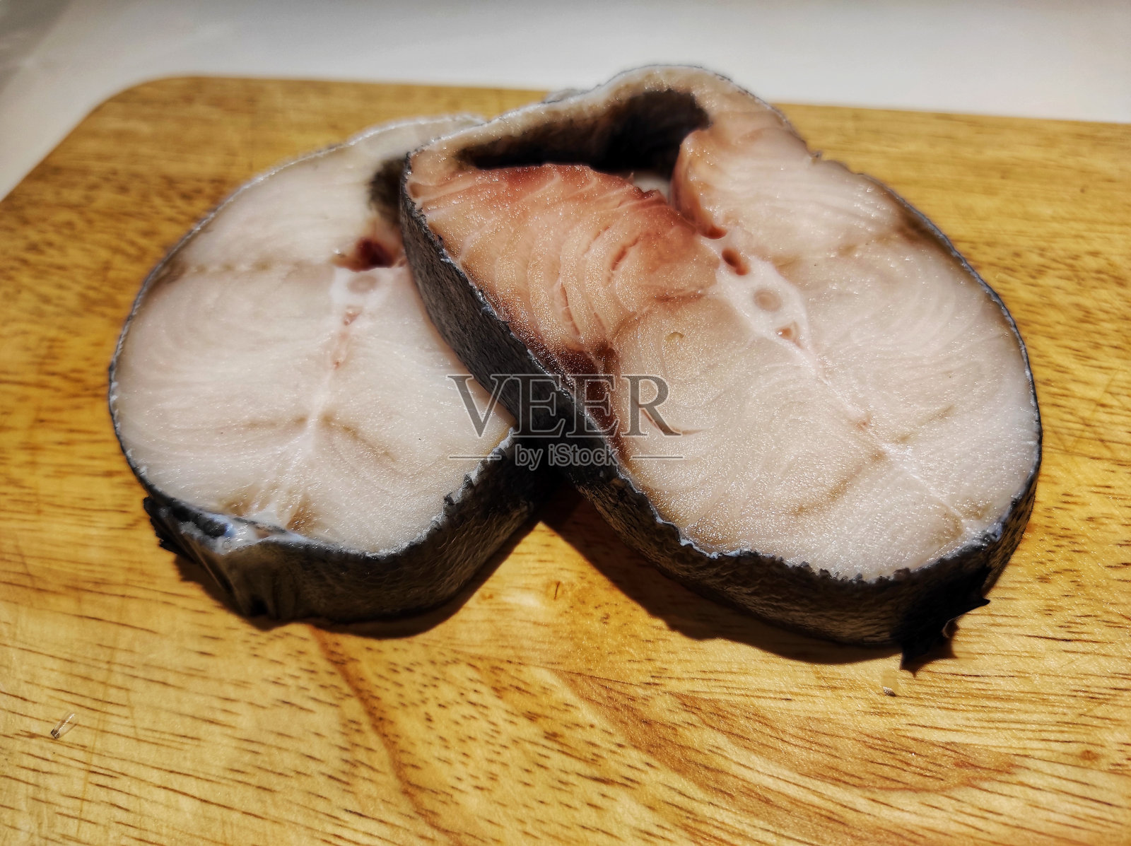 两块生鲭鱼或Scomberomorini放在木板上。照片摄影图片