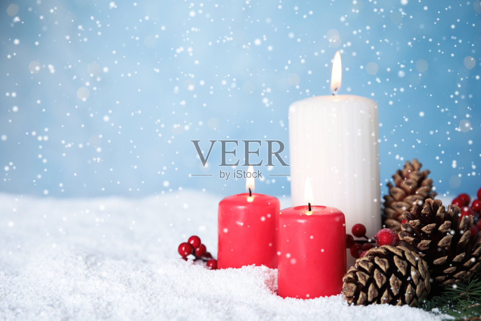 雪花落在燃烧的蜡烛和松果对浅蓝色的背景，文字的空间。圣诞夜照片摄影图片