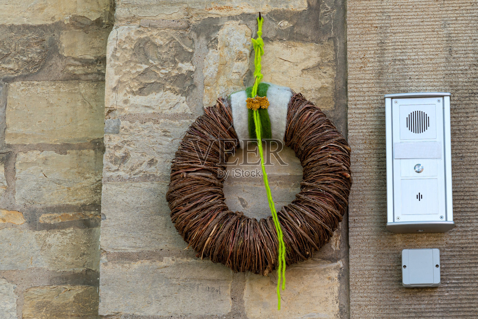 用干树枝编织的花环挂在石墙上。照片摄影图片
