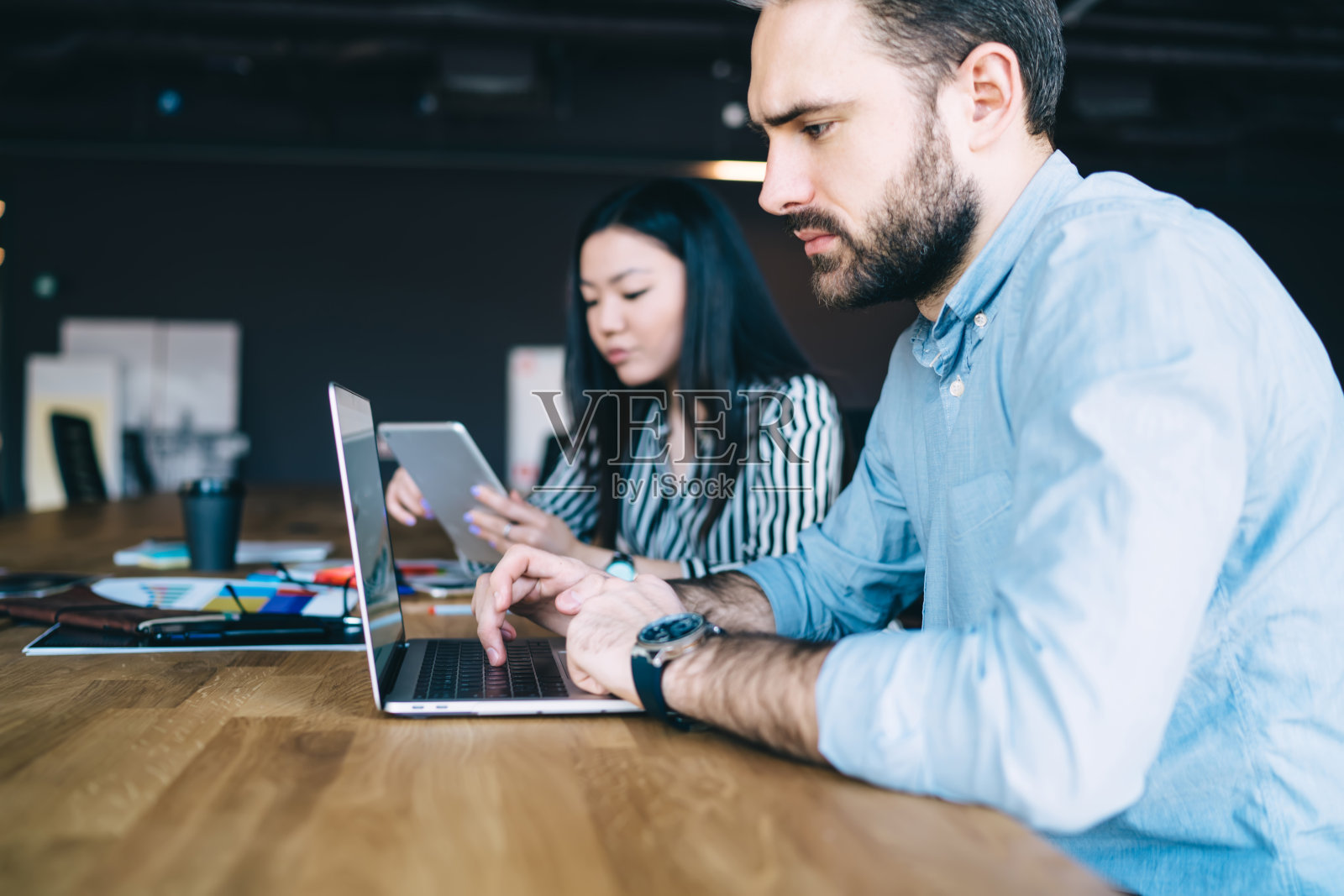 年轻夫妇在工作场所使用电子设备照片摄影图片