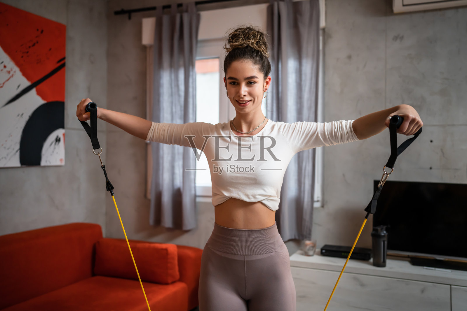 一个女人美丽的女性训练在家里的房间里使用橡胶电阻带管，女运动员单独做运动的健康和健身概念拷贝空间照片摄影图片