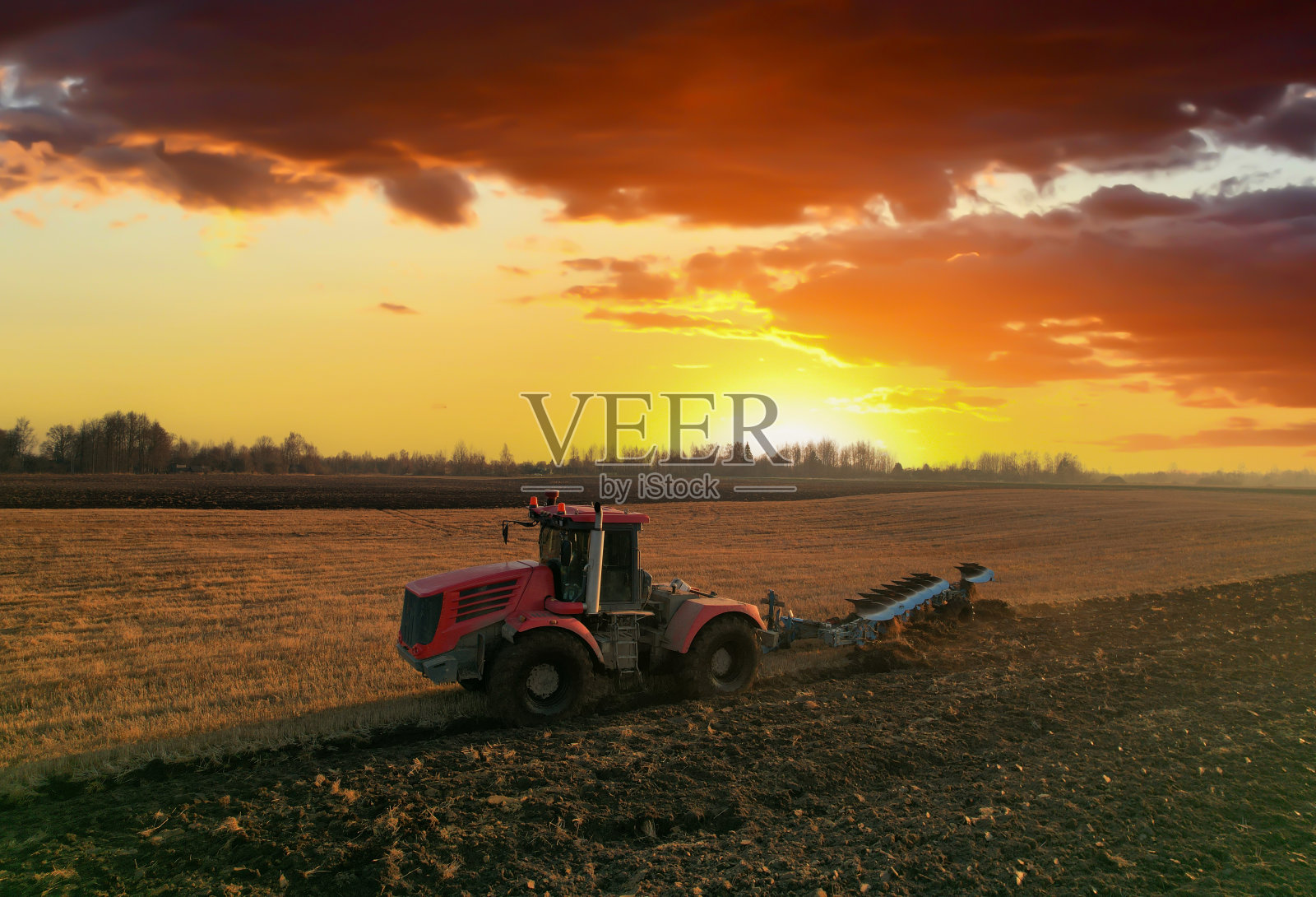 拖拉机在日落时犁地。耕地和土壤耕作。照片摄影图片