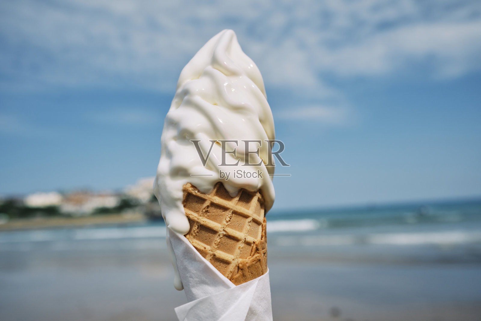 六月的一个阳光明媚的日子，康沃尔郡纽基镇海滩，手拿着冰淇淋。照片摄影图片