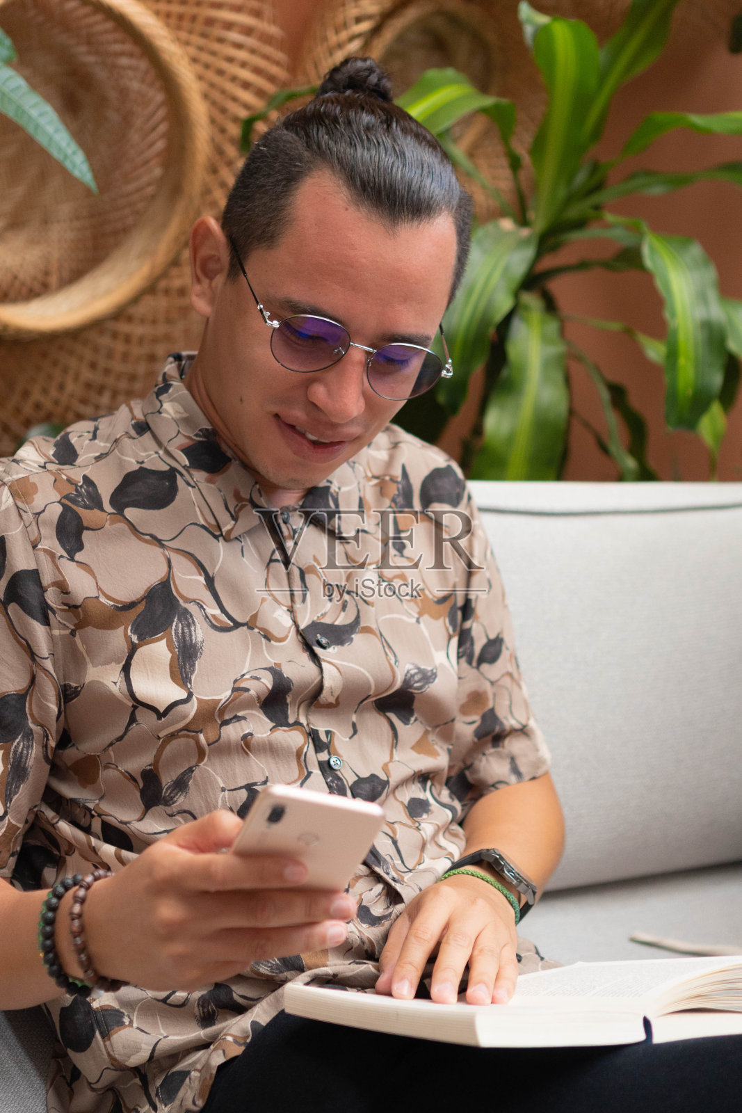 拉丁人坐在扶手椅上看手机。照片摄影图片