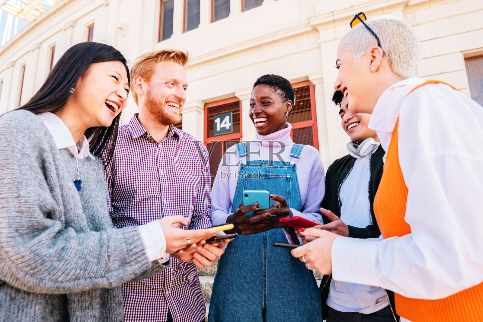 年轻人拿着手机在户外嬉笑打闹。照片摄影图片