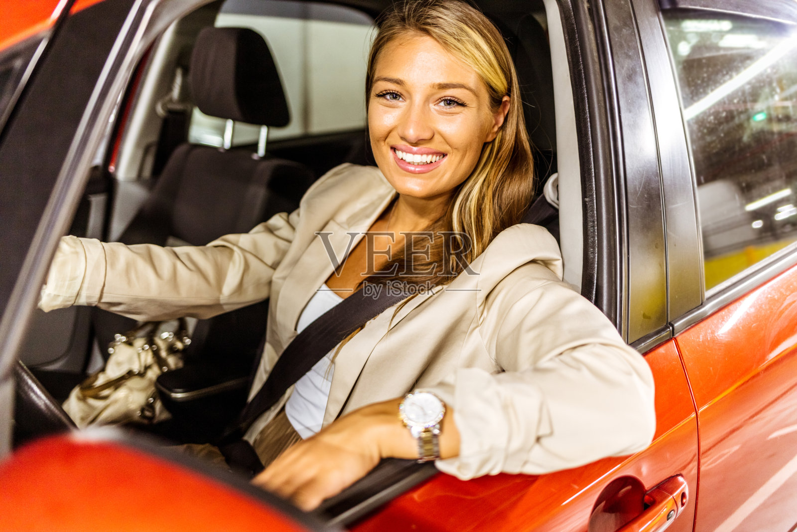 拍摄了一个开朗的年轻女商人开车上班，她的手臂在白天伸出车外。漂亮的白人女人开着她的新车。照片摄影图片