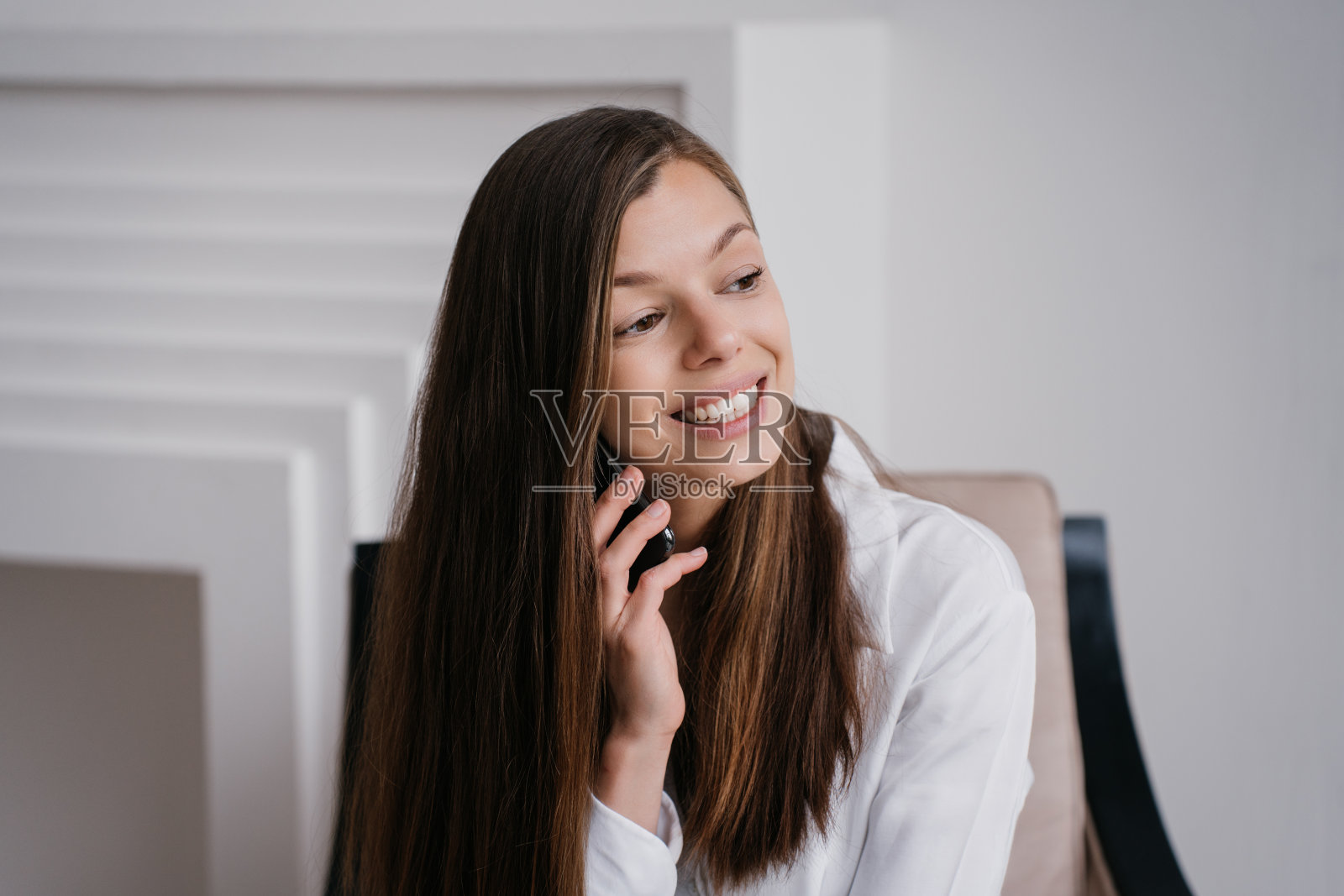 兴奋的欧洲年轻女子打电话，笑得很灿烂，看着一边。成功的西班牙女商人与合伙人交谈。开朗漂亮的女学生在家里享受周末的早晨。照片摄影图片