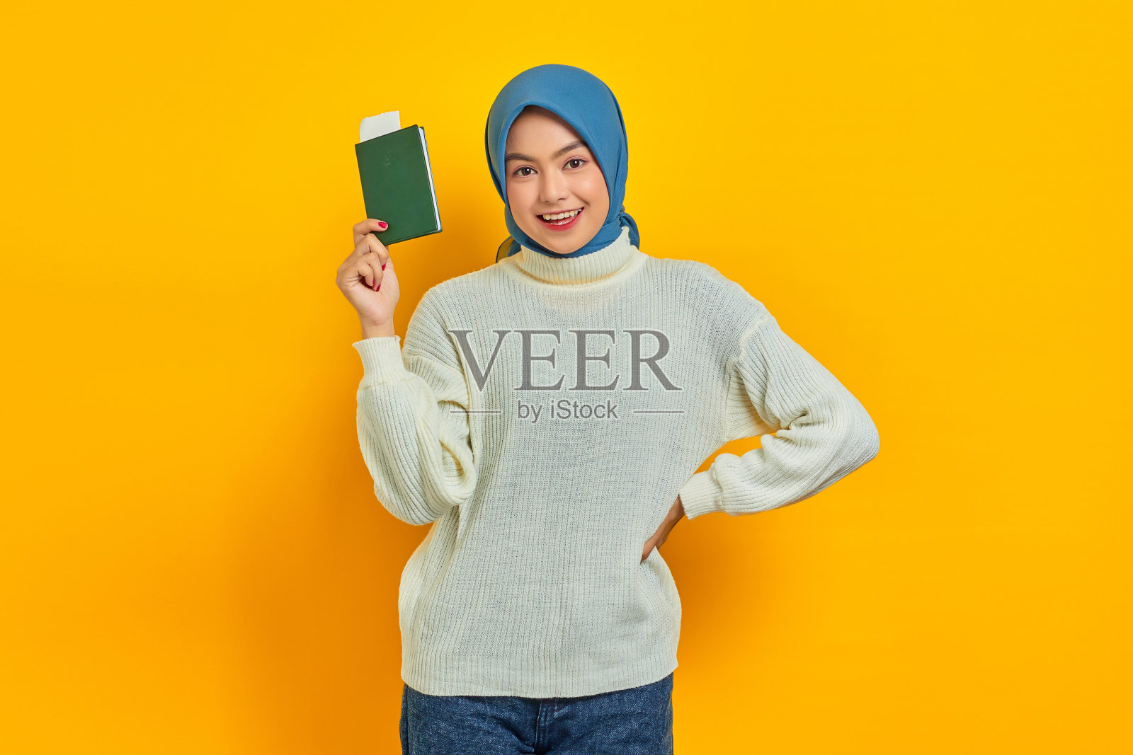 微笑美丽的亚洲女人在白色毛衣显示护照孤立的黄色背景。夏天的旅行照片摄影图片