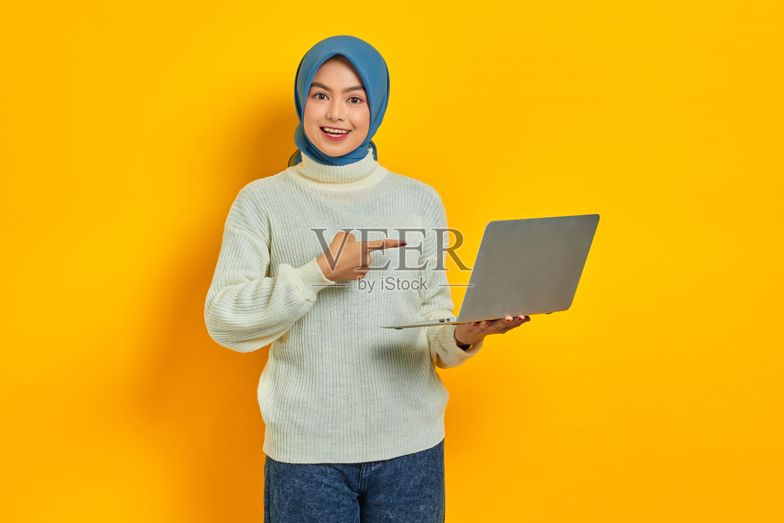 开朗美丽的亚洲女人穿着白色毛衣使用笔记本电脑，收到好消息邮件孤立孤立的黄色背景。人们的宗教生活方式观念照片摄影图片