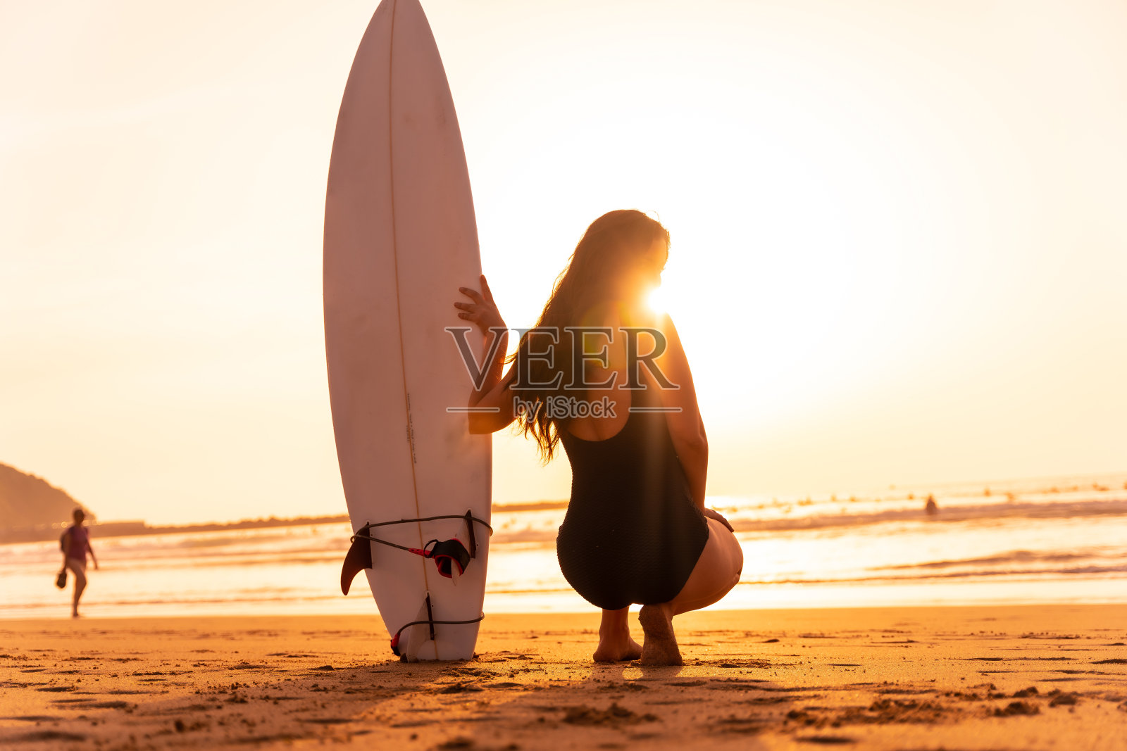 美丽的冲浪女人在海滩上的日落。印度尼西亚巴厘岛。照片摄影图片