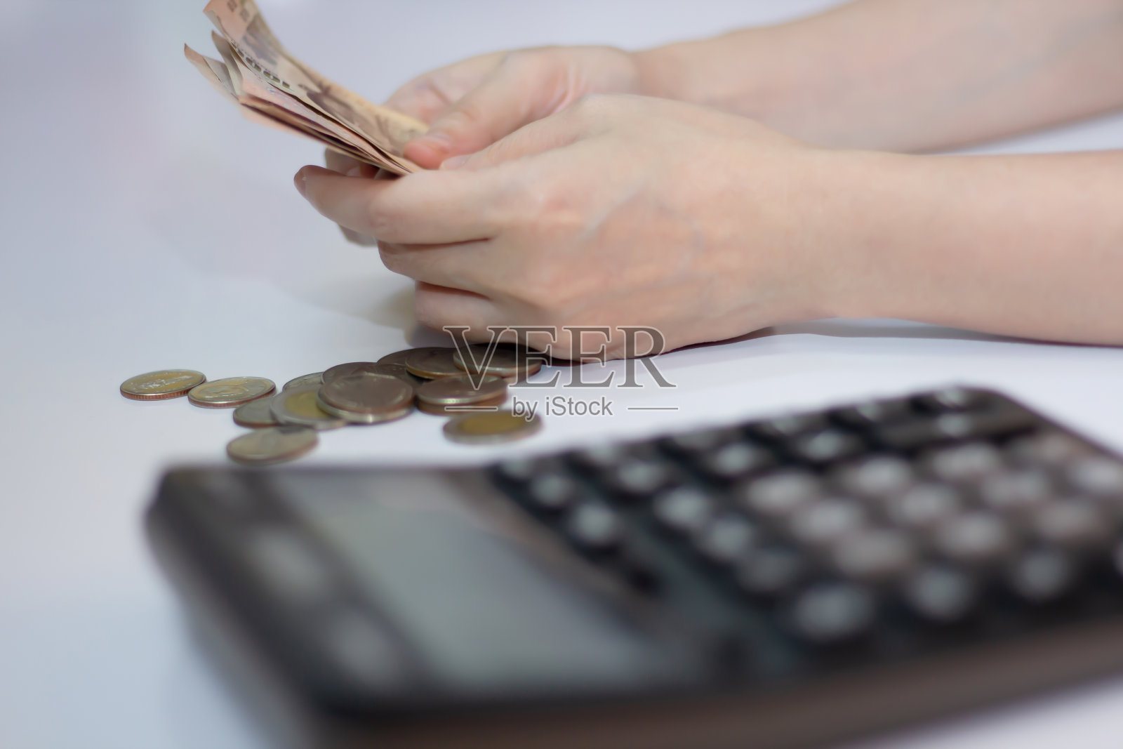 女人用硬币和计算器数钱，省钱的观念。照片摄影图片
