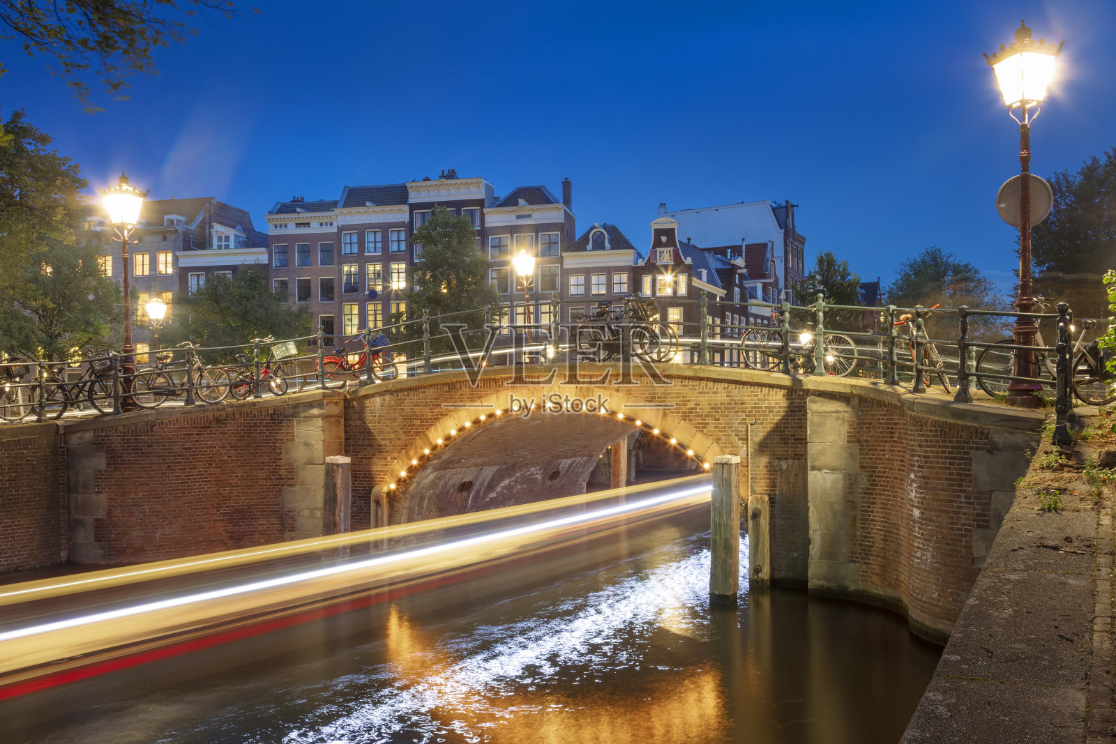 阿姆斯特丹的夜晚。街道上的灯光和船的移动留下的痕迹。在阿姆斯特丹老城漫步是个不错的夜晚。照片摄影图片