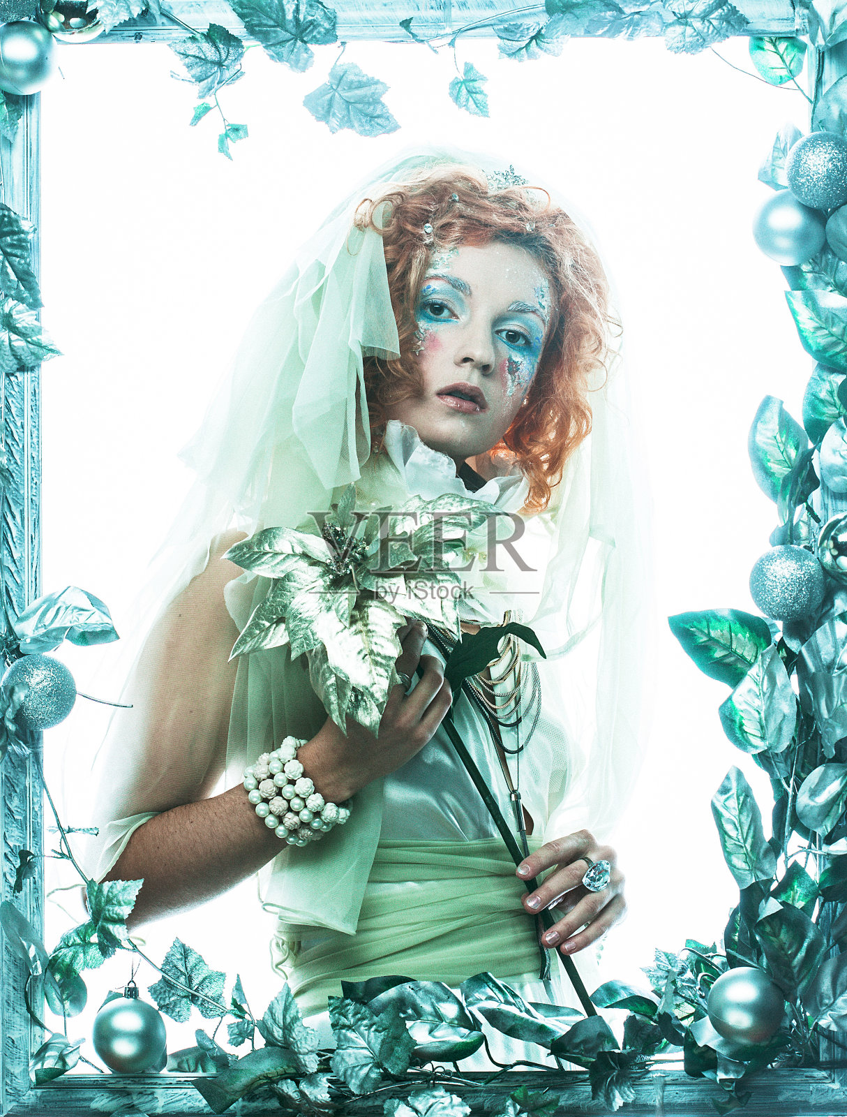 一位美丽的姜黄色女子穿着圣诞嘉年华的服装，在圣诞装饰品的框架中摆姿势。照片摄影图片