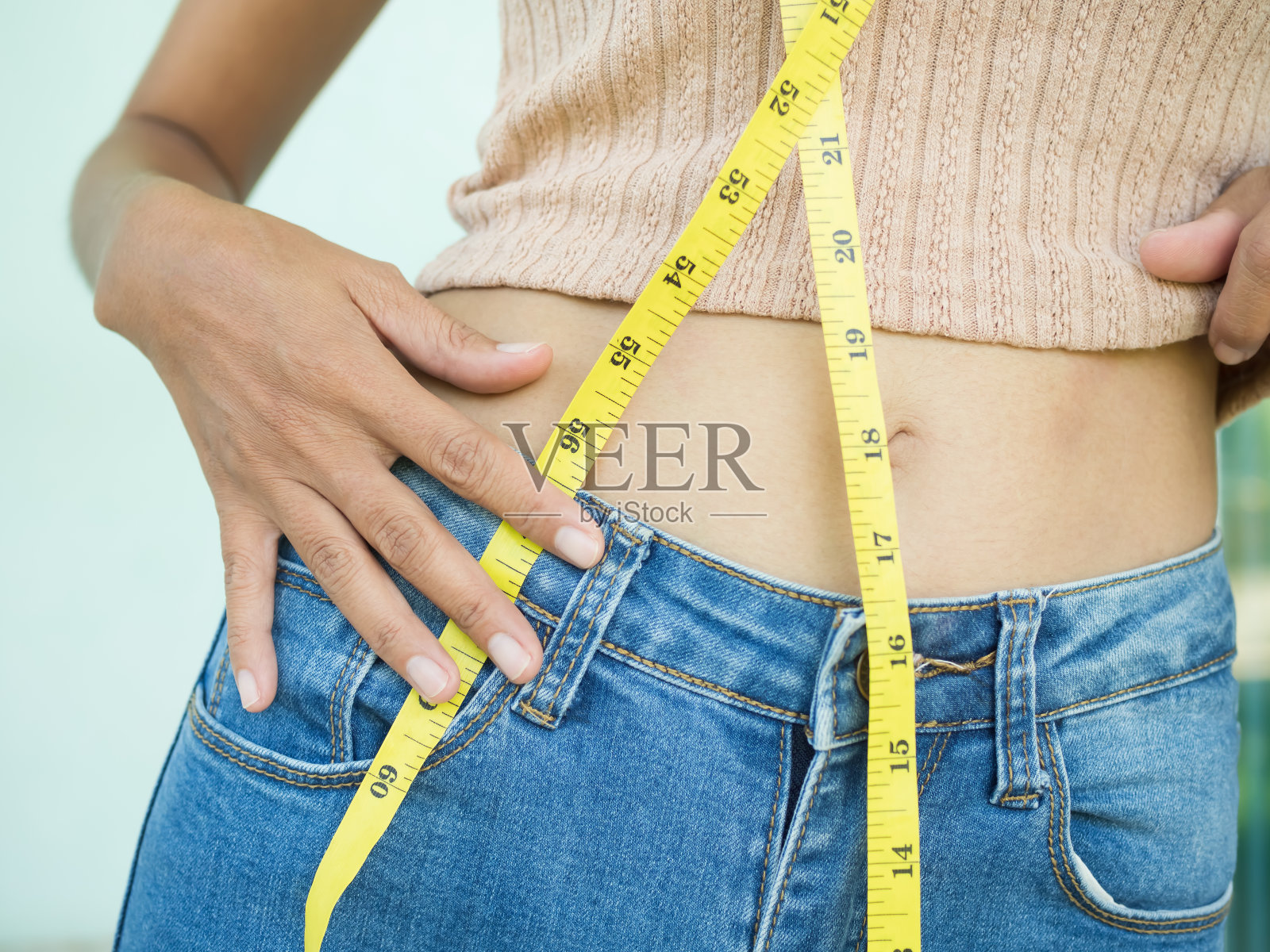 腰女人与牛仔裤卷尺。身材苗条身材匀称的年轻女孩。照片摄影图片