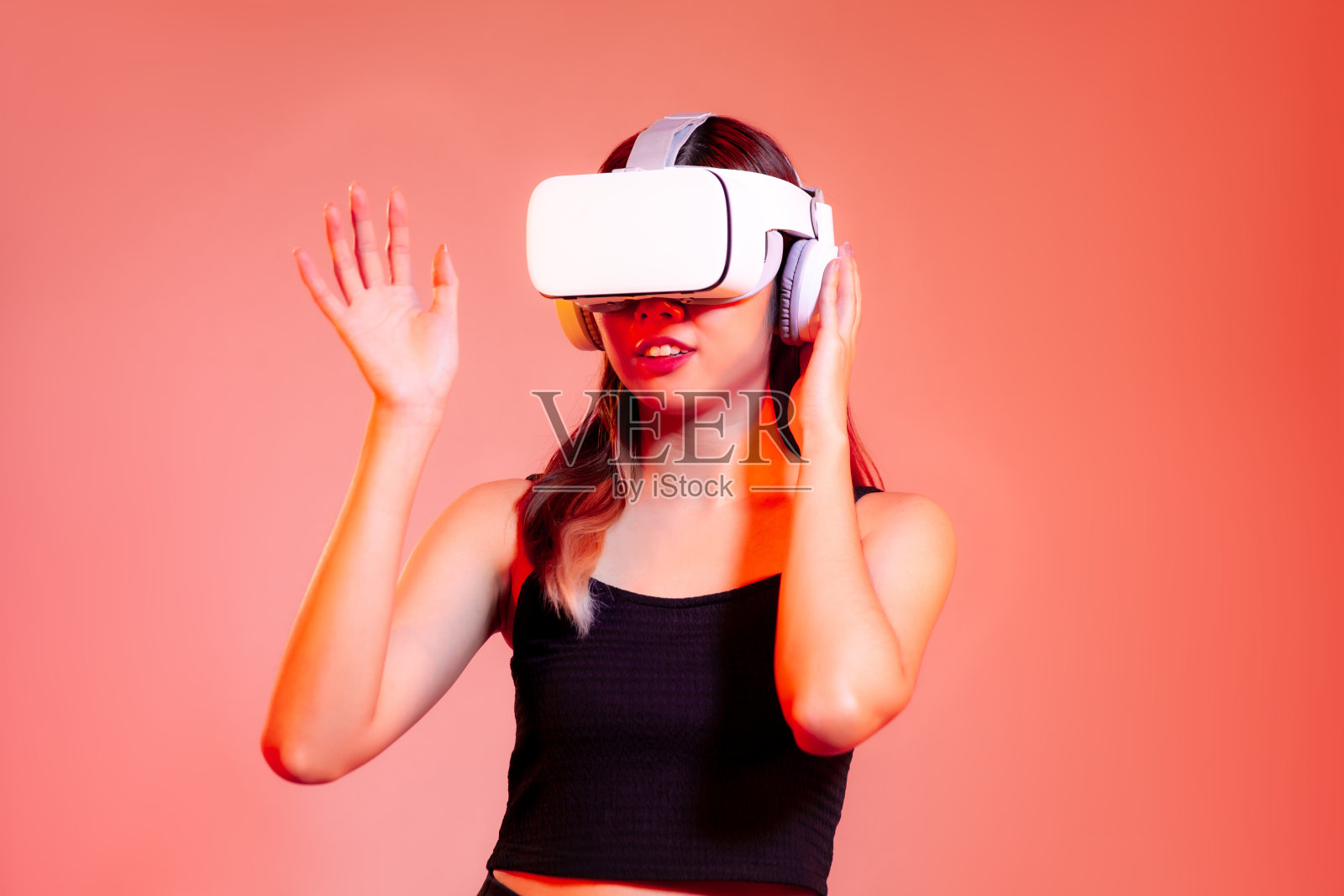 Metaverse概念，年轻的亚洲女性在黑色背心穿着白色vr头盔观看玩和触摸的红色粉彩屏幕背景照片摄影图片